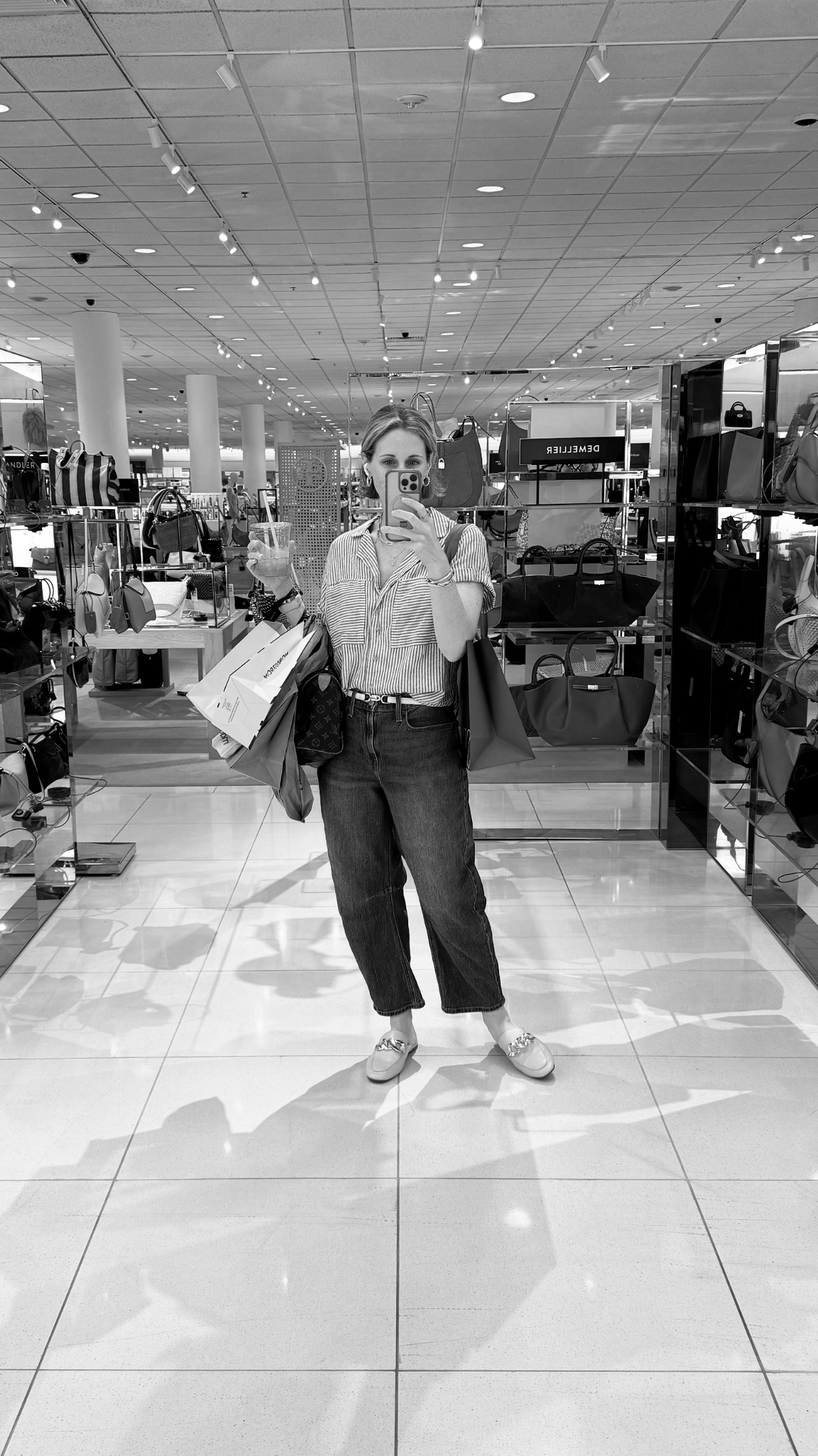 Woman shopping in a department store, taking a mirror selfie with shopping bags in her hand, personal shopper, personal wardrobe stylist