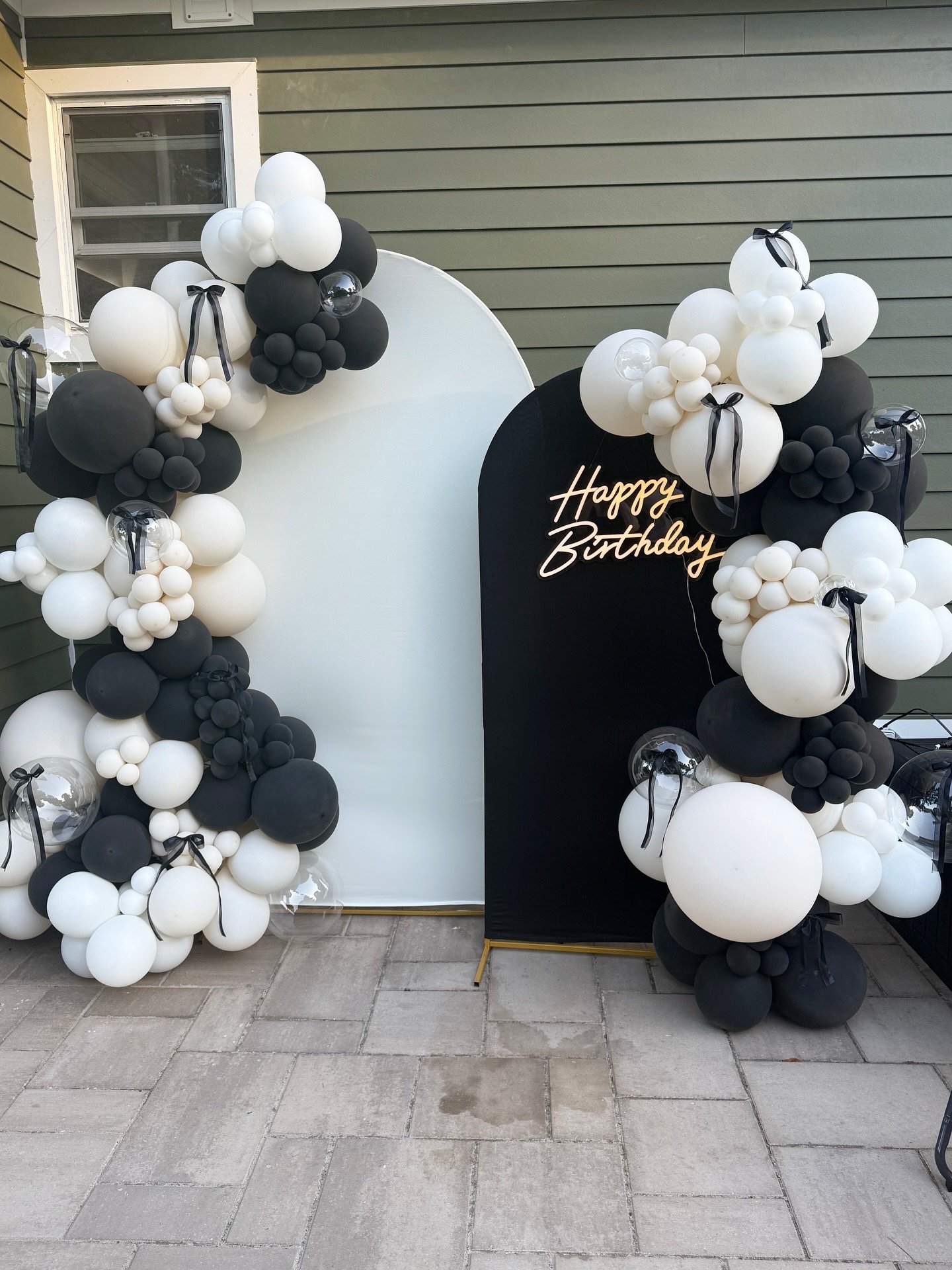 Black and white balloon arch with a "Happy Birthday" sign on a black board