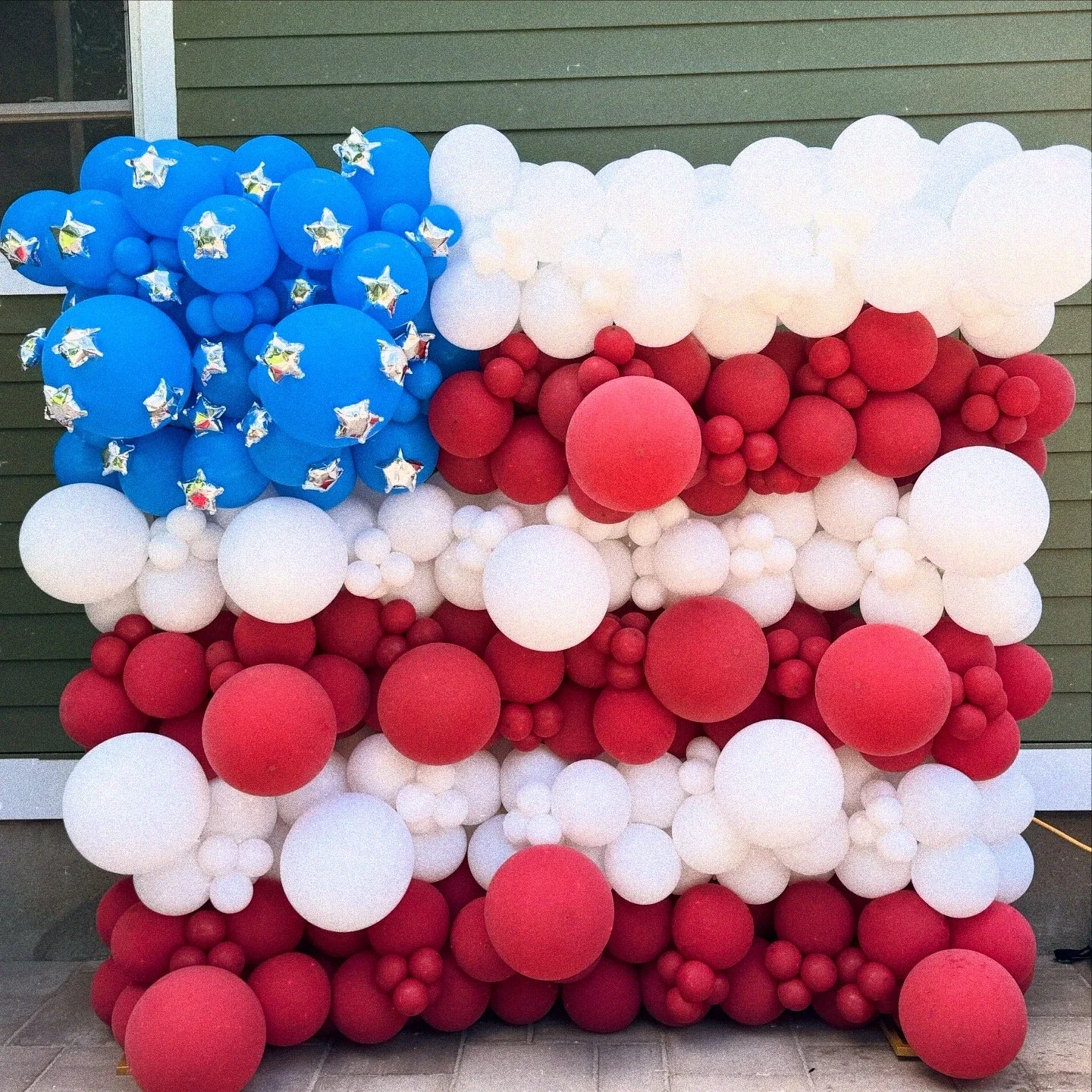 Balloon arrangement resembling the American flag with blue stars, white stripes, and red bands.