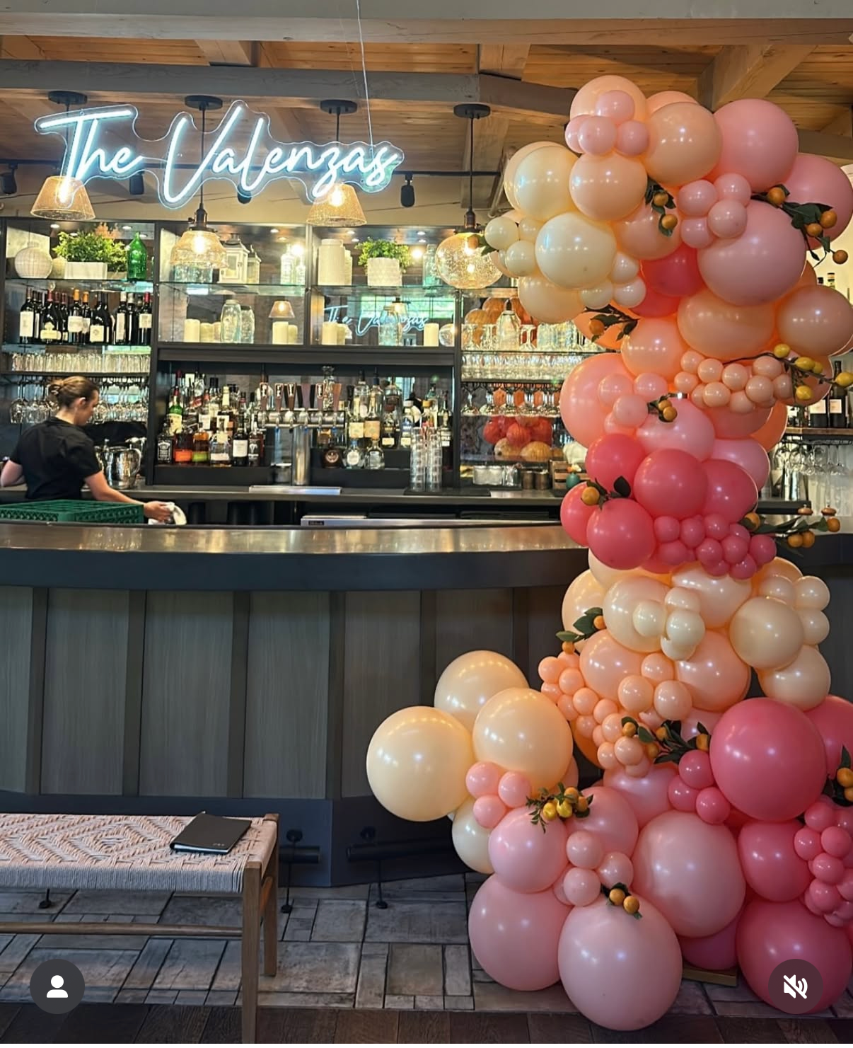 A bar area decorated with a large pink and cream balloon arrangement and a neon sign that says "The Valencia."