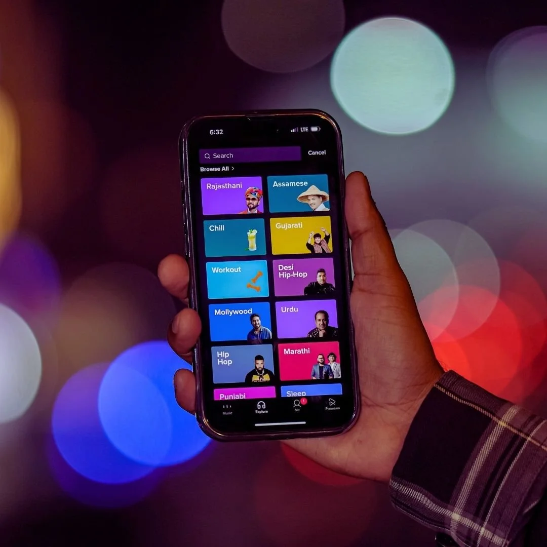 A hand holdking an iphone that has i tunes opened on it.