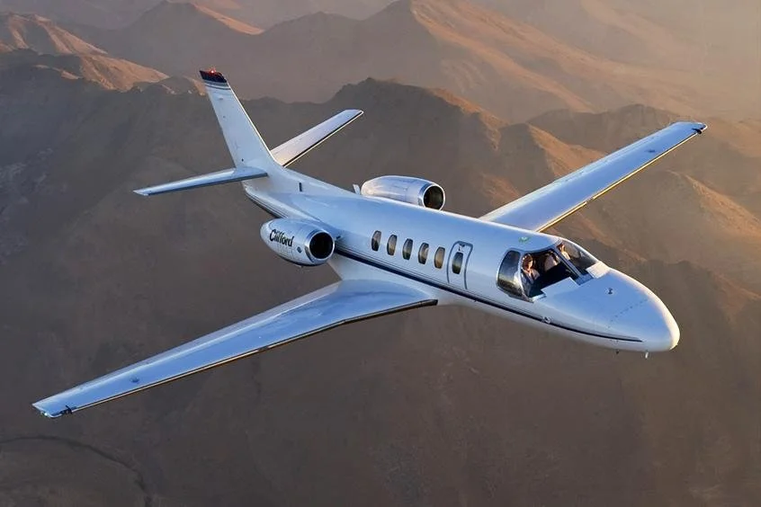 Cessna Citation Bravo private jet parked on an airport apron under a bright blue sky.
