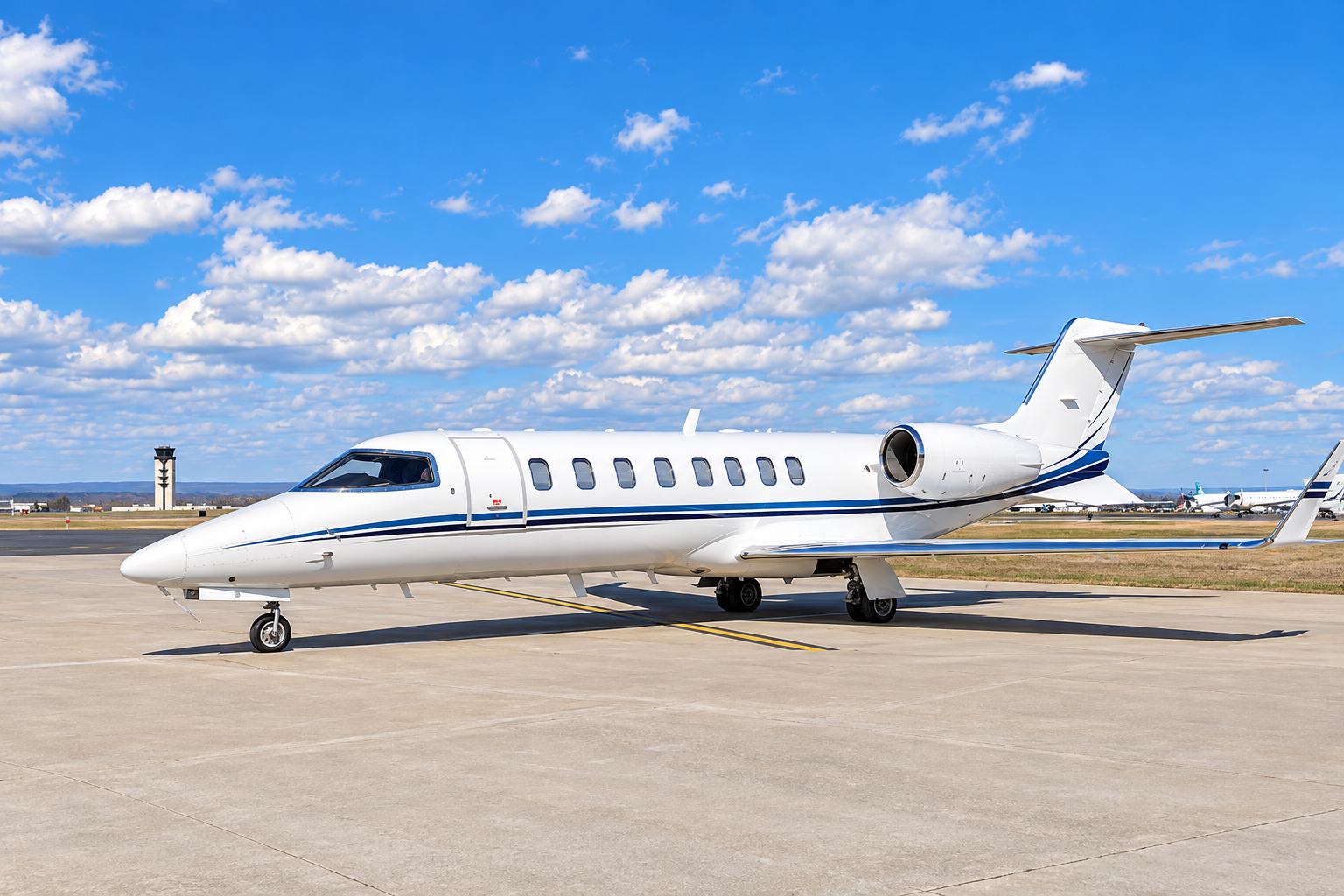 Learjet 45 private jet parked on an airport apron, shown in a bright exterior side view under a blue sky with scattered clouds.