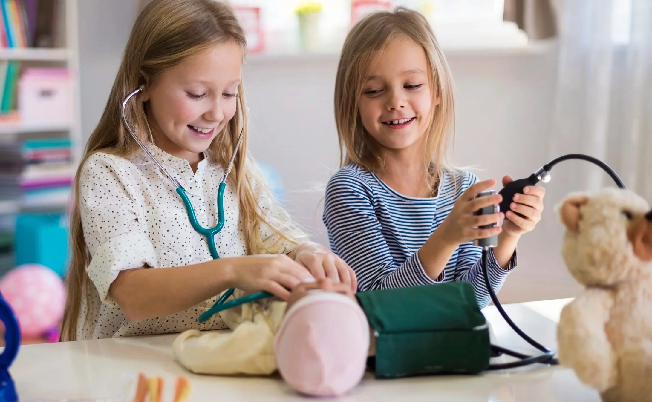 Two young girls playing doctor together with a stethoscope and medical toys, representing the collaborative and playful spirit of pediatric care supported by Flourish Therapy Service in Athens, GA.