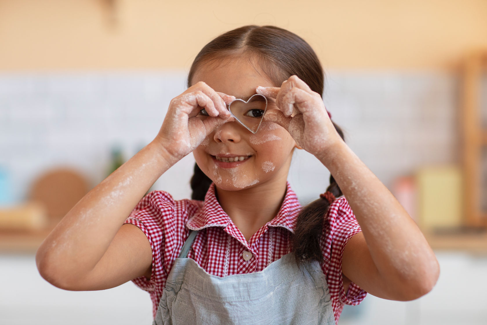 Young girl making a heart shape with her hands and smiling, representing the joyful and family-centered approach to pediatric occupational therapy at Flourish Therapy Service in Athens, GA.