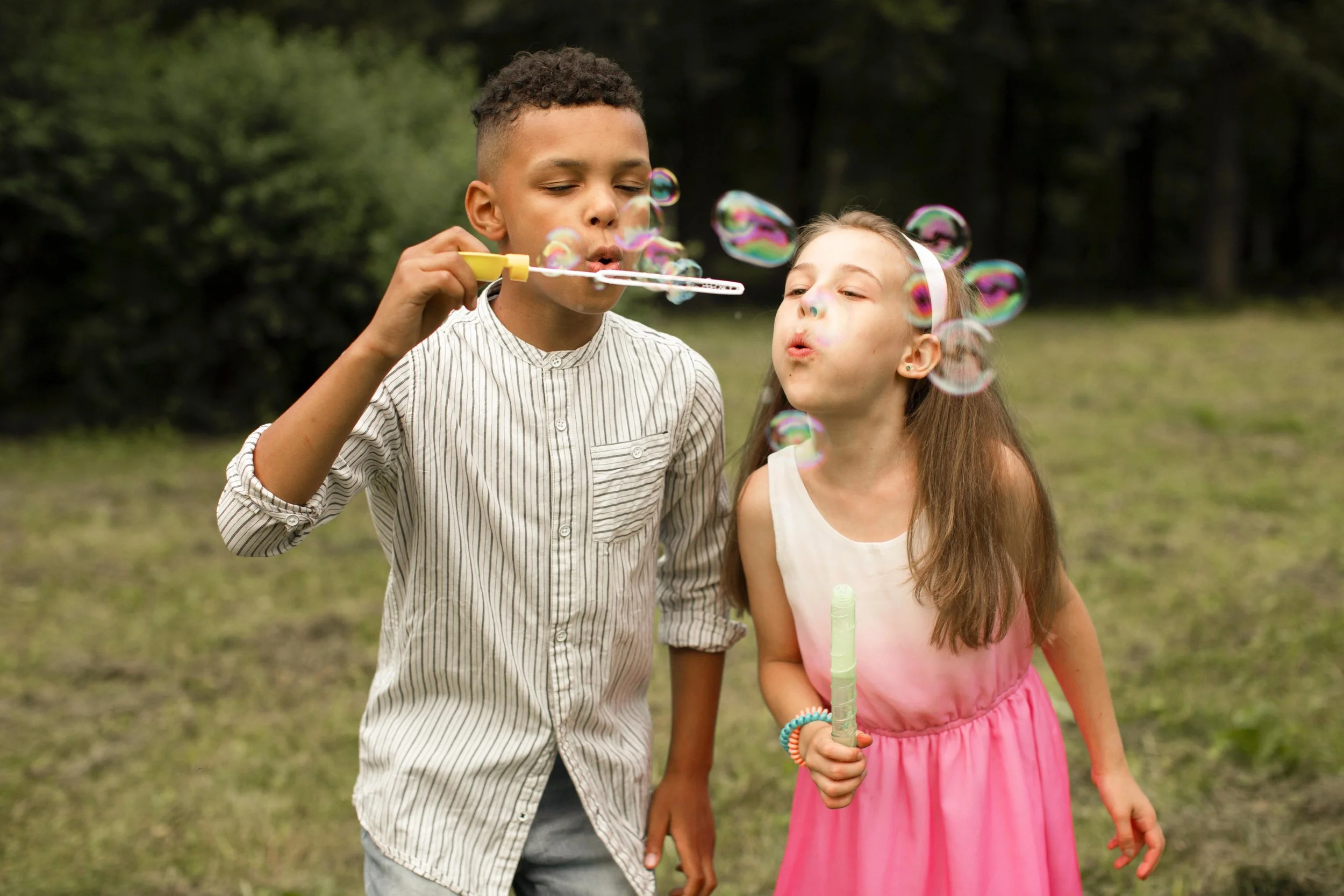 Two children joyfully blowing bubbles together outdoors, representing the carefree and playful spirit of childhood supported by pediatric occupational therapy services at Flourish Therapy Service in Athens, GA.