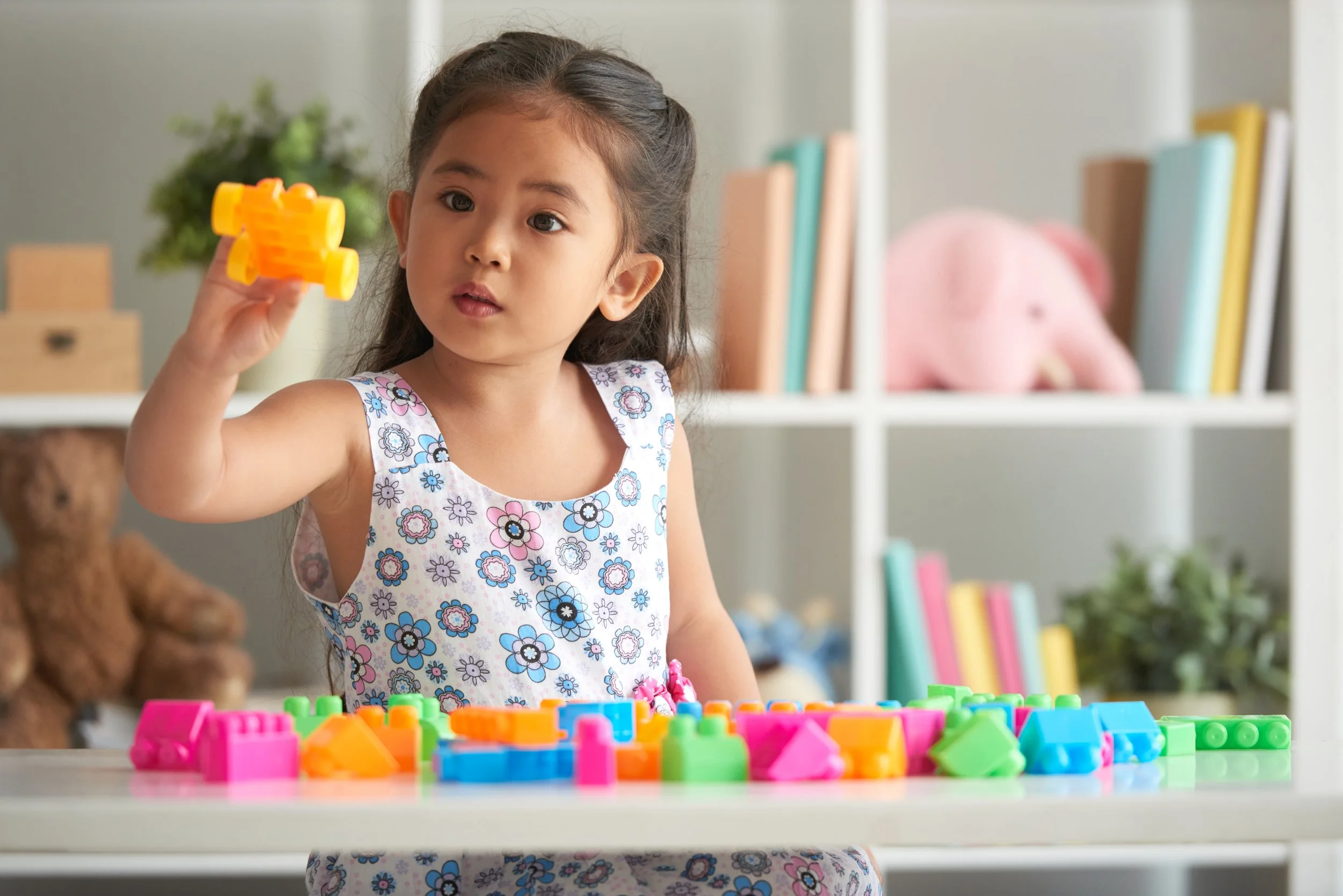 Young girl focused on building with colorful blocks, representing the engaging and skill-building approach to pediatric occupational therapy at Flourish Therapy Service in Athens, GA.