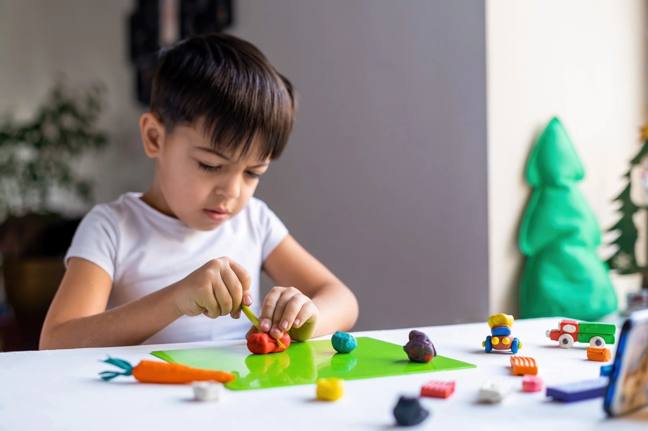 Young boy focused on sculpting with colorful clay, developing fine motor and sensory processing skills through pediatric occupational therapy at Flourish Therapy Service in Athens, GA.