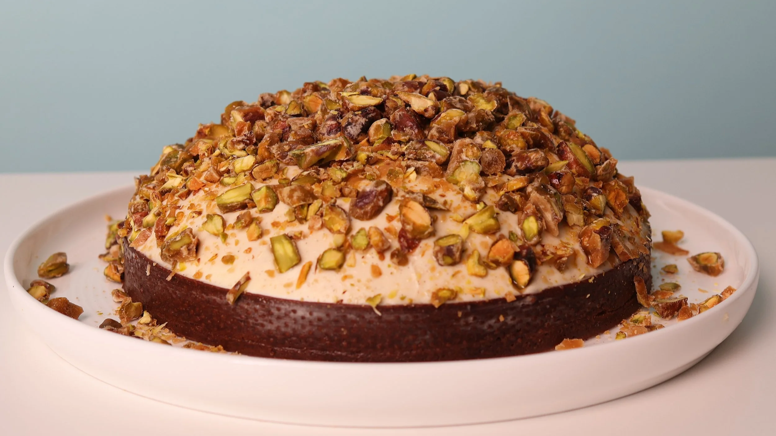 A beautiful domed Chocolate tart willed with pistachio praline and vanilla and pistachio chantilly topped with caramelized pistachios.