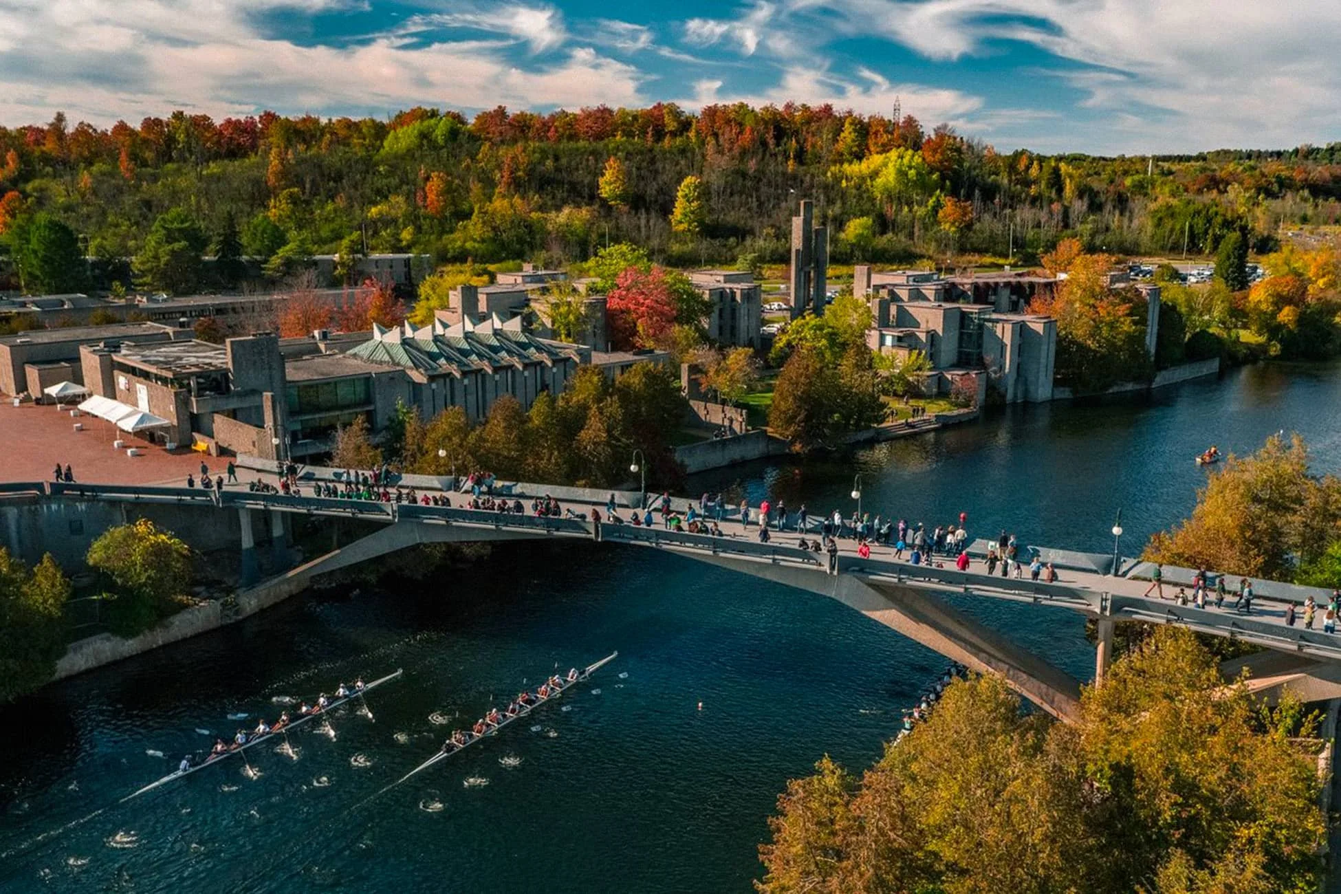 Aerial image of Trent river and Trent University with bridge and rowers below