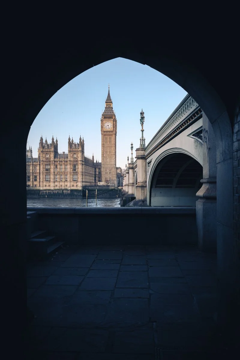 View of Big Ben and the Houses of Parliament in London, UK, taken from a tunnel or archway near the Westminster Bridge over the River Thames.