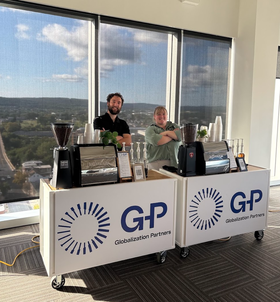 Two professional baristas behind two custom-branded espresso carts at a corporate event