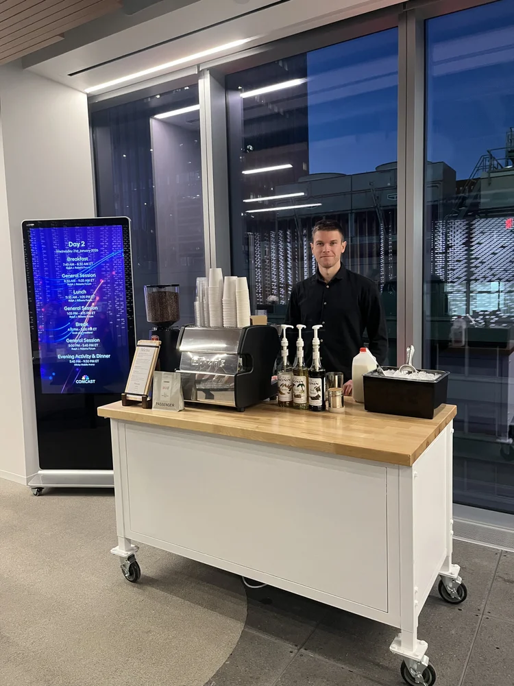 Professional barista staffing a mobile espresso cart at a Comcast event