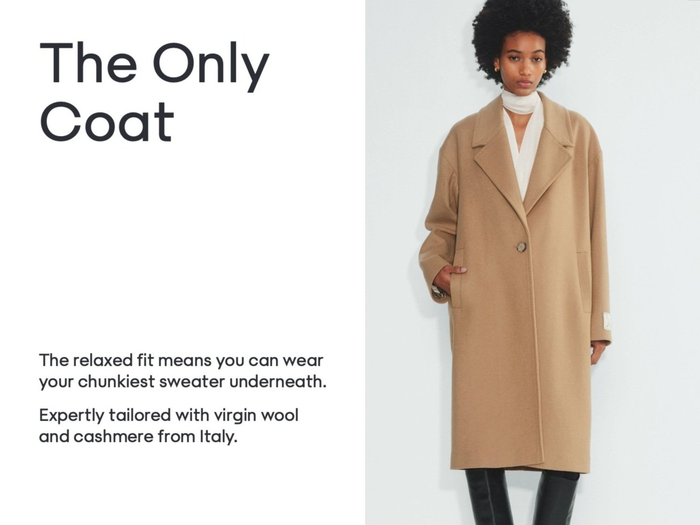 Advertisement for a camel-colored, long, relaxed-fit coat with a wide lapel, worn open over a white top, modeled by a woman with natural curly hair against a plain background.