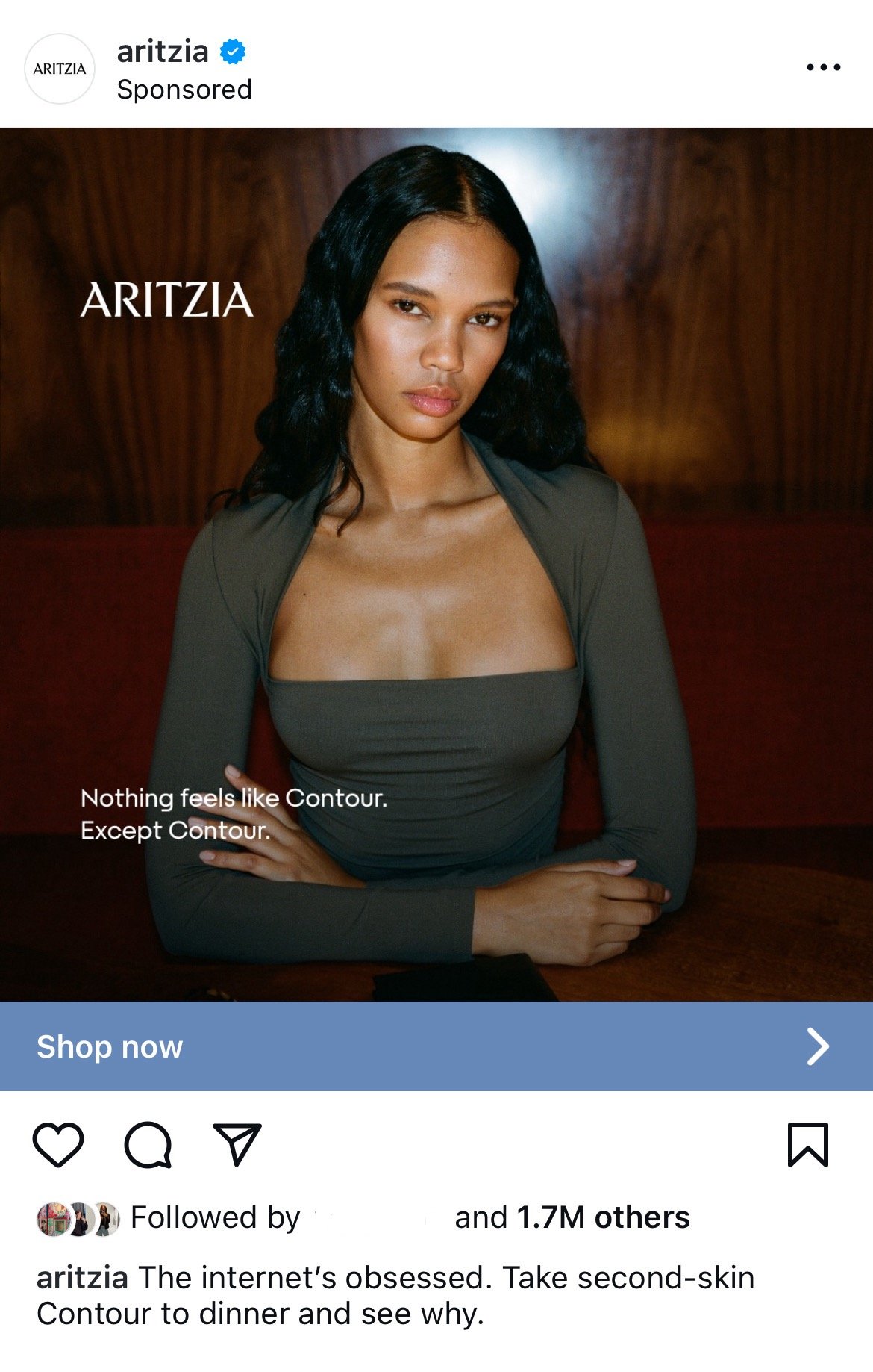 A woman with long black wavy hair sitting at a table, wearing a form-fitting dark green dress with a square neckline. The background is wooden, and there is a blue banner with text that reads "Shop now." The overlay text says: 'Nothing feels like Contour. Except Contour.'