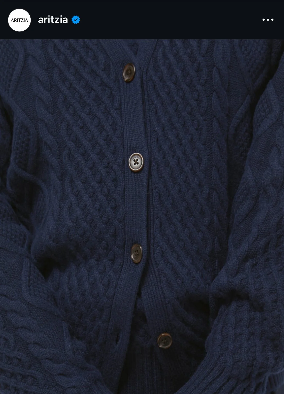 Close-up of a navy blue cable-knit cardigan with four buttons.