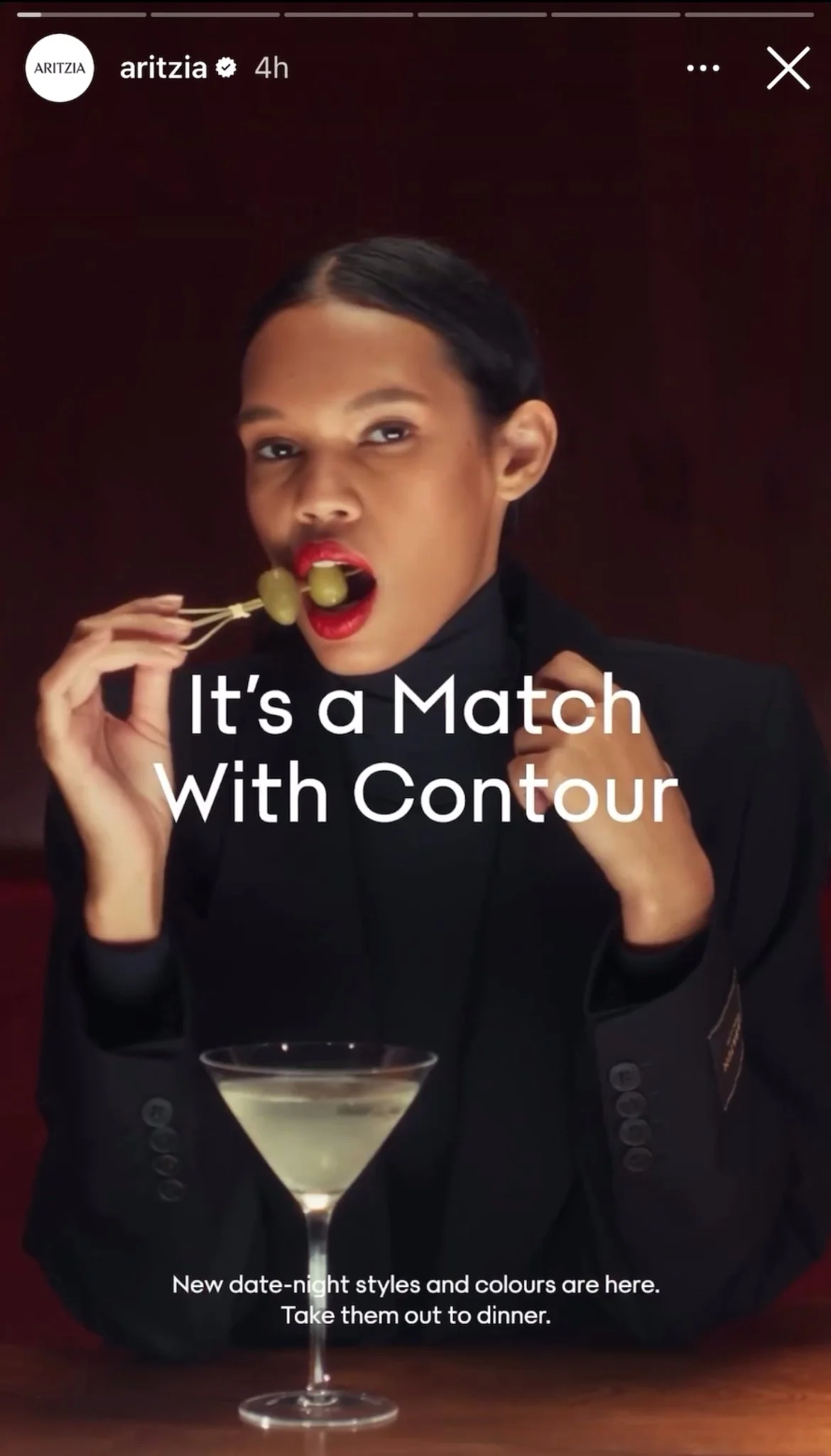 A woman with dark hair styled back, wearing a black blazer, holding two green grapes on a toothpick, and sitting at a table with a martini glass full of a clear drink. Text on the image reads, 'It's a Match With Contour.'