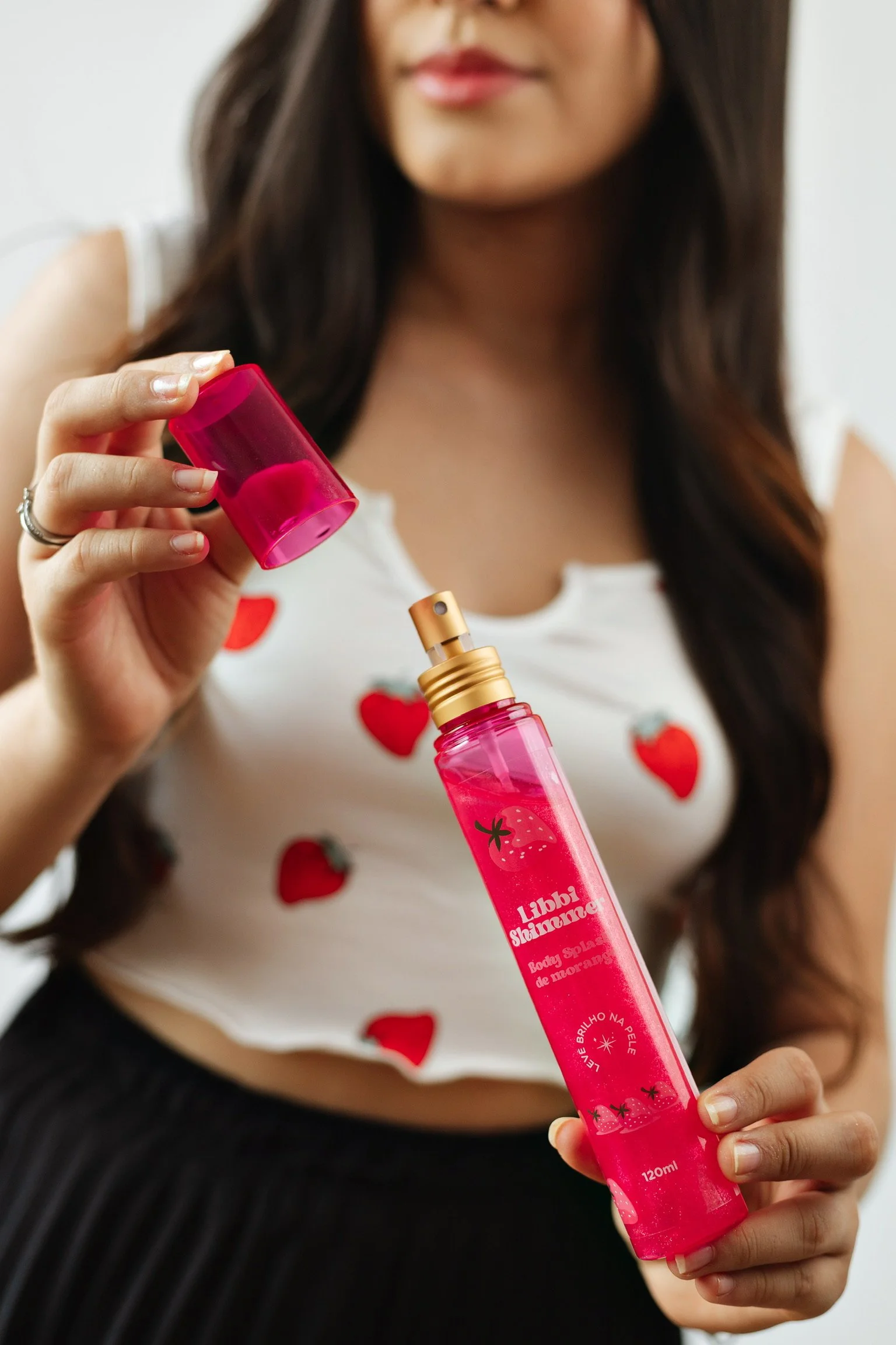 modelo segurando embalagem e tampa do body splash da marca Libbi