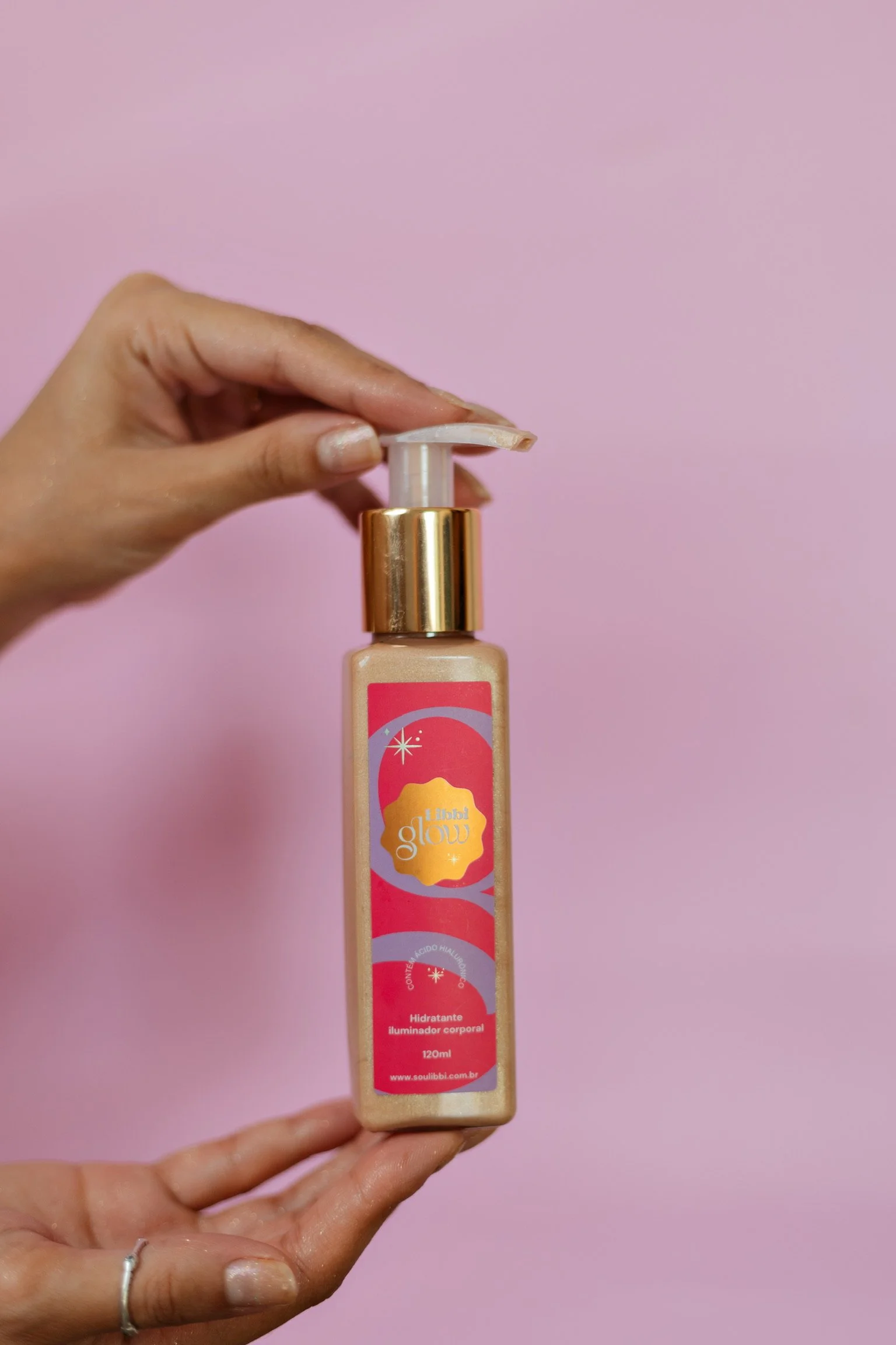 mão segurando embalagem do hidratante iluminador corporal da marca Libbi