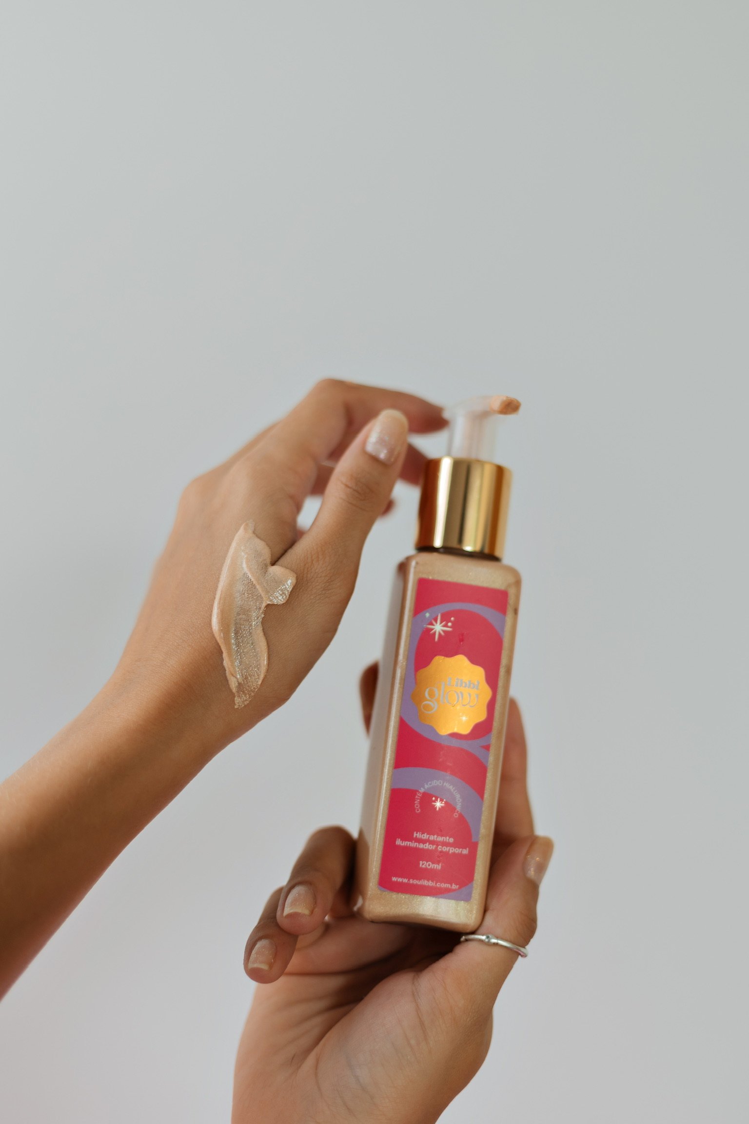 mão segurando embalagem do hidratante iluminador corporal da marca Libbi
