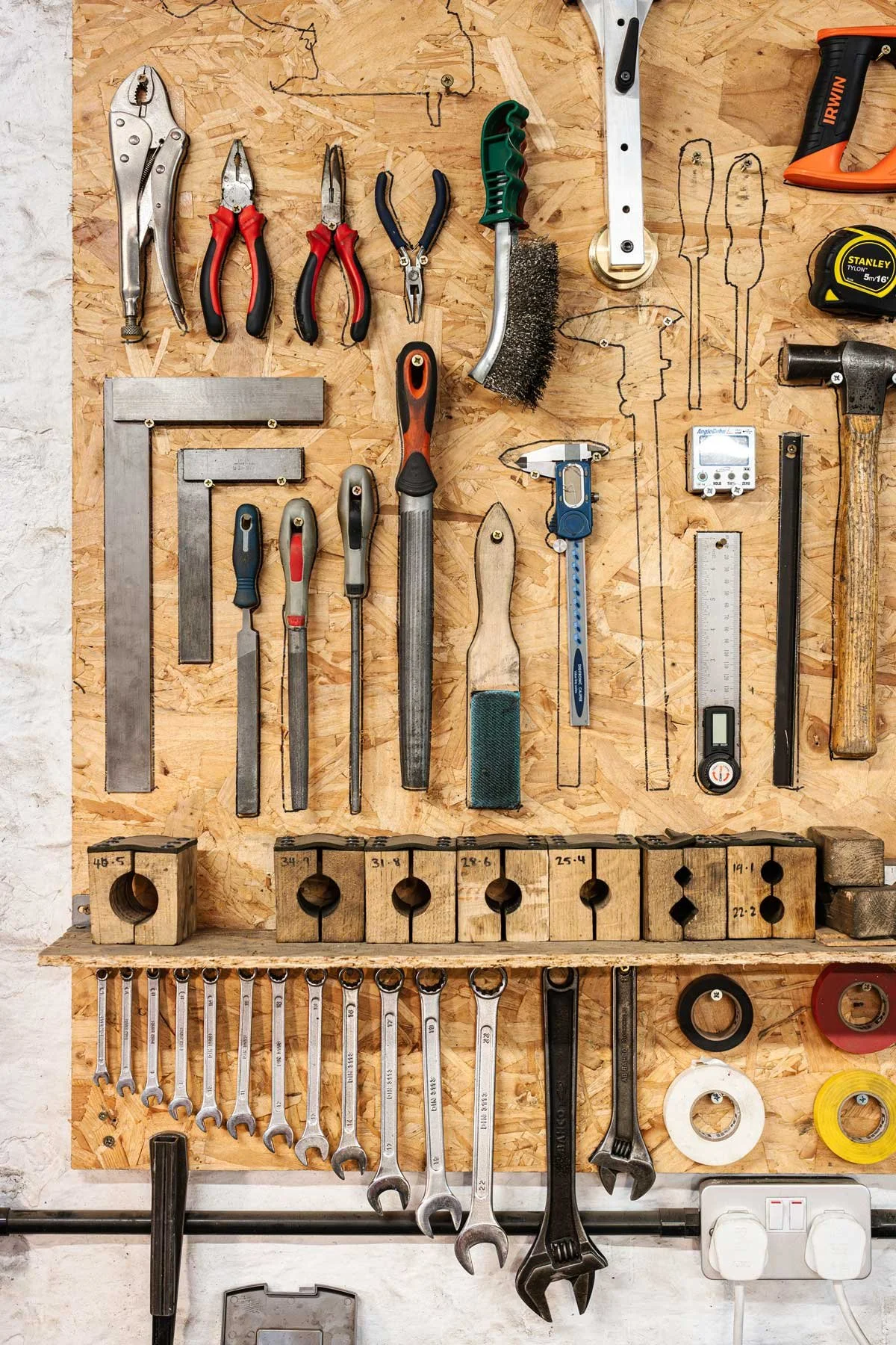 A workshop toolboard, showing tools such as wooden bicycle tube blocks and metal right angle squares.