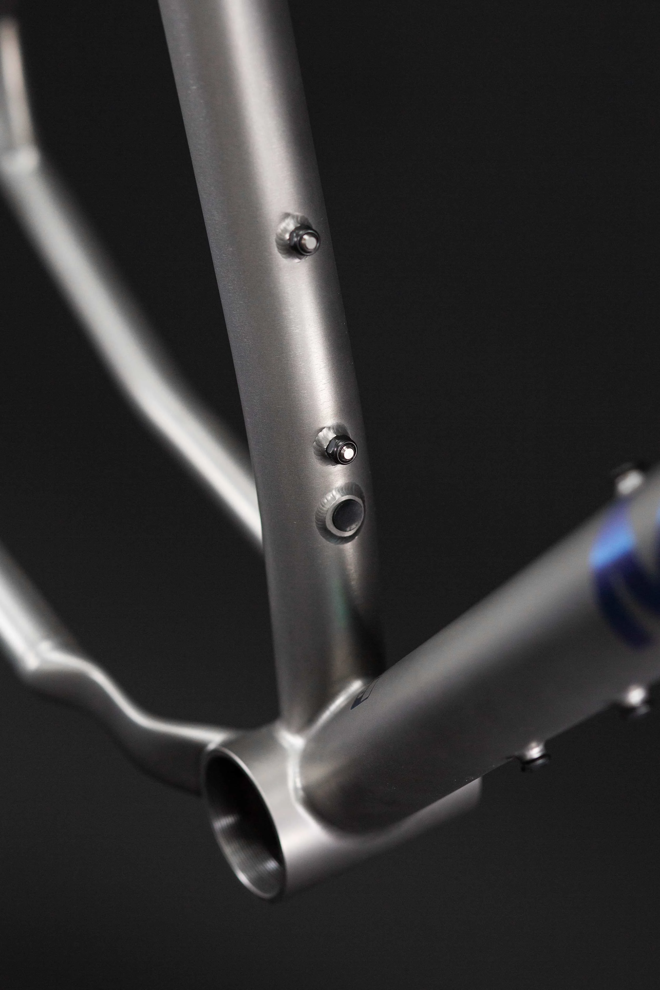 A close-up of the seat tube on the Zapr titanium frame, showcasing the meticulous UK-made welds, dropper routing and external bottle boss mounts allowing for deep seat post insertion.