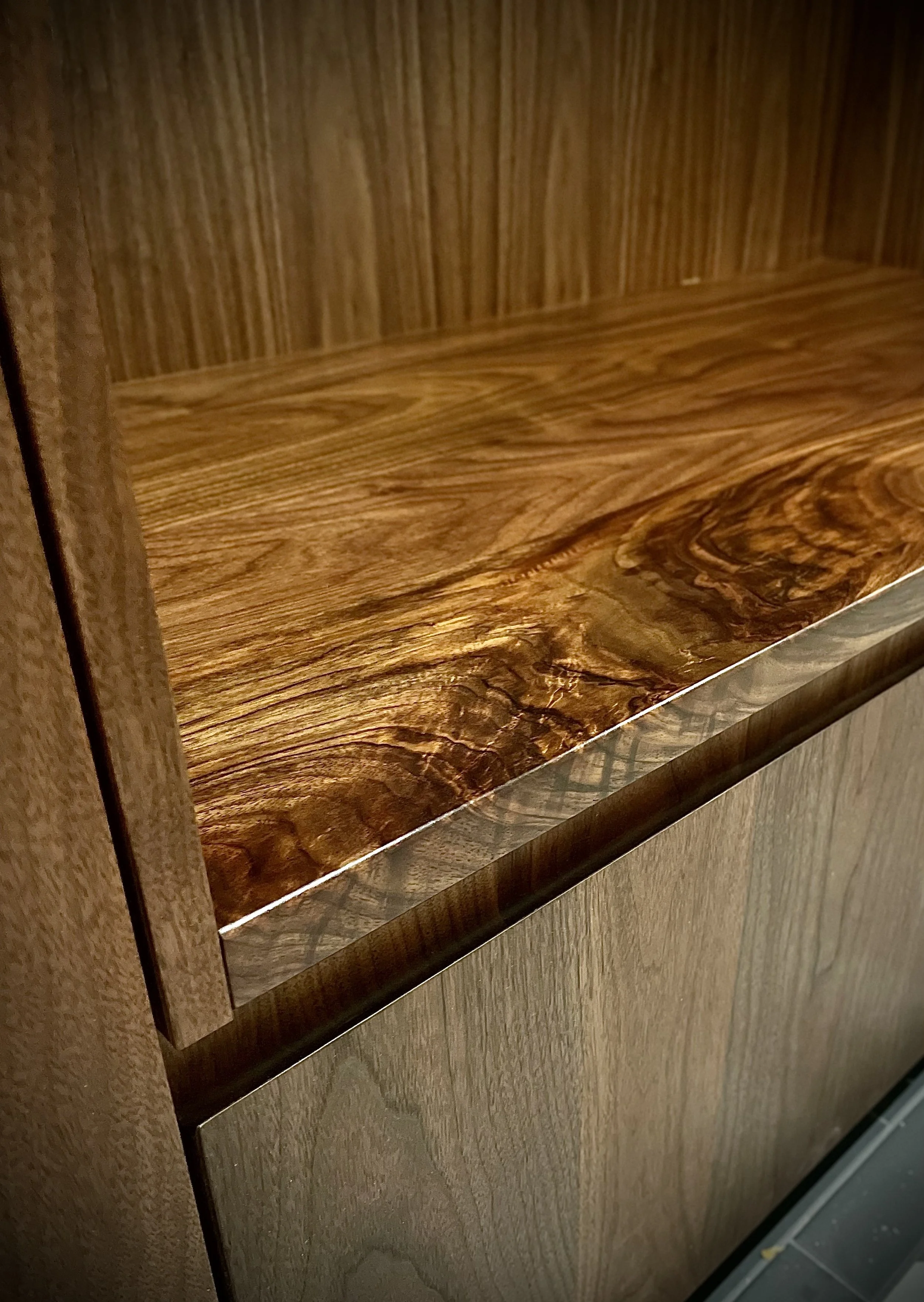 Close-up of a wooden cabinet showing the top surface with a natural wood grain pattern and a polished finish.