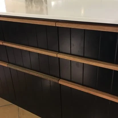 Empty black shelves with wooden edges against a white countertop.