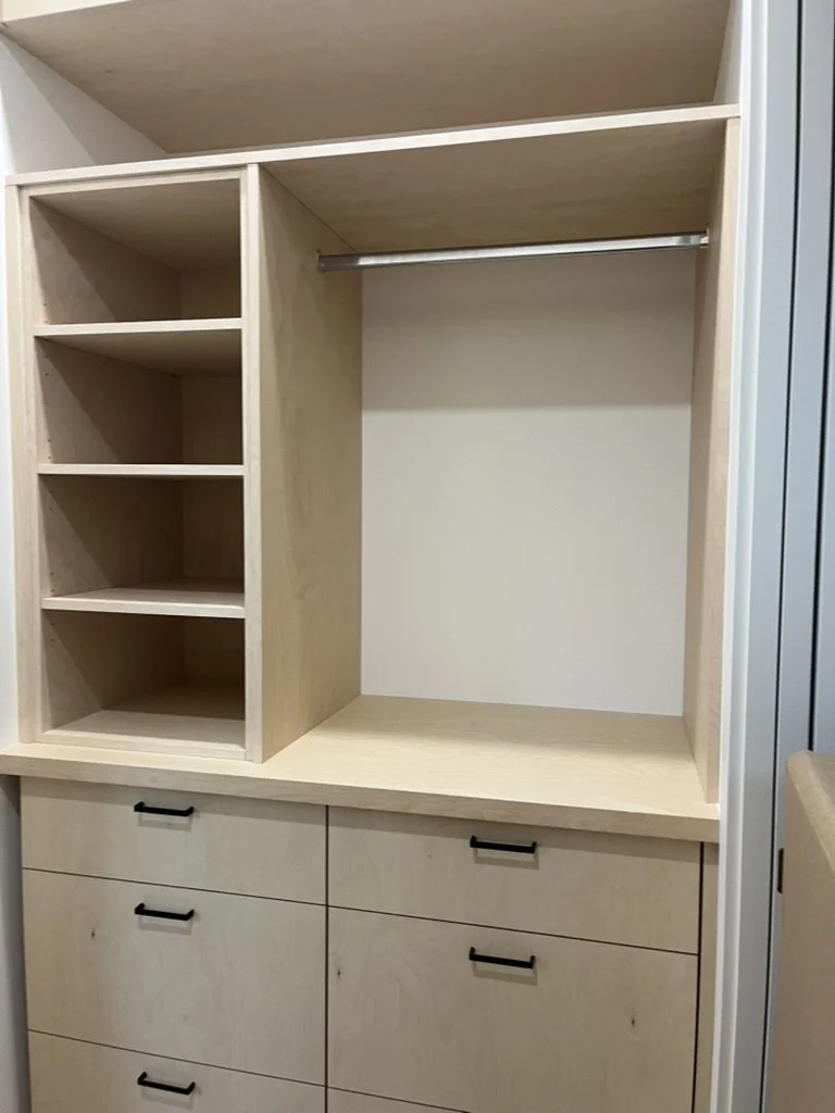 Empty built-in closet with shelves, a hanging rod, and drawers.