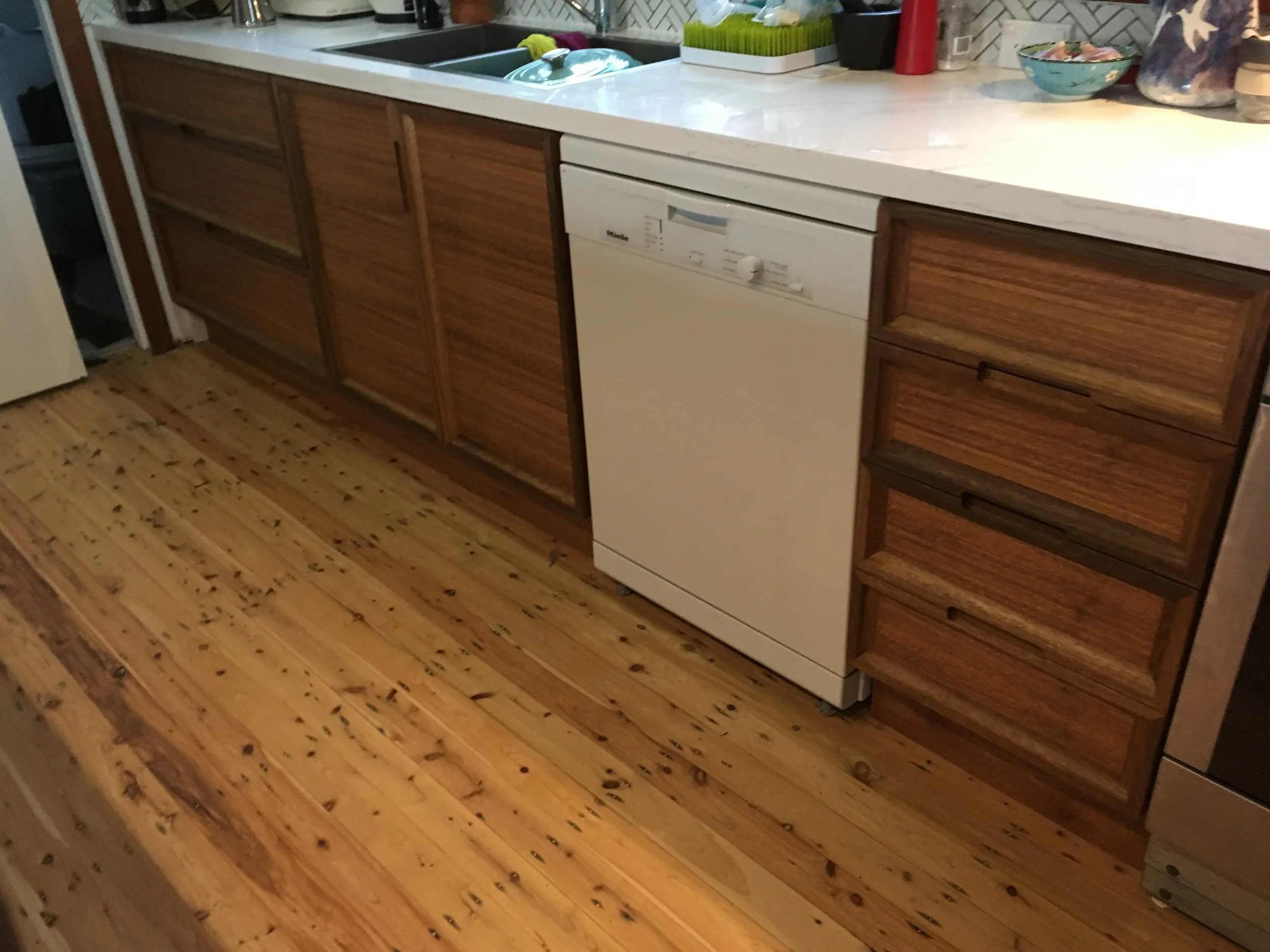 Kitchen with wooden cabinets, white countertop, dishwasher, and hardwood floor.