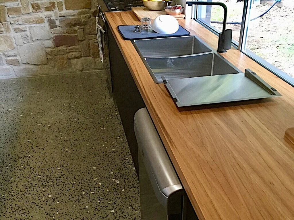 Kitchen counter with a sink, faucet, and drying rack near a window.