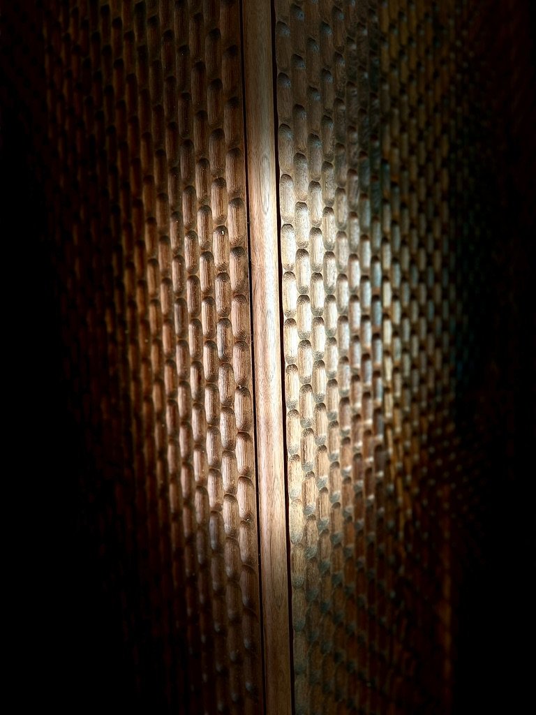 Close-up of a wooden surface with a textured, patterned design, illuminated in the center with light.
