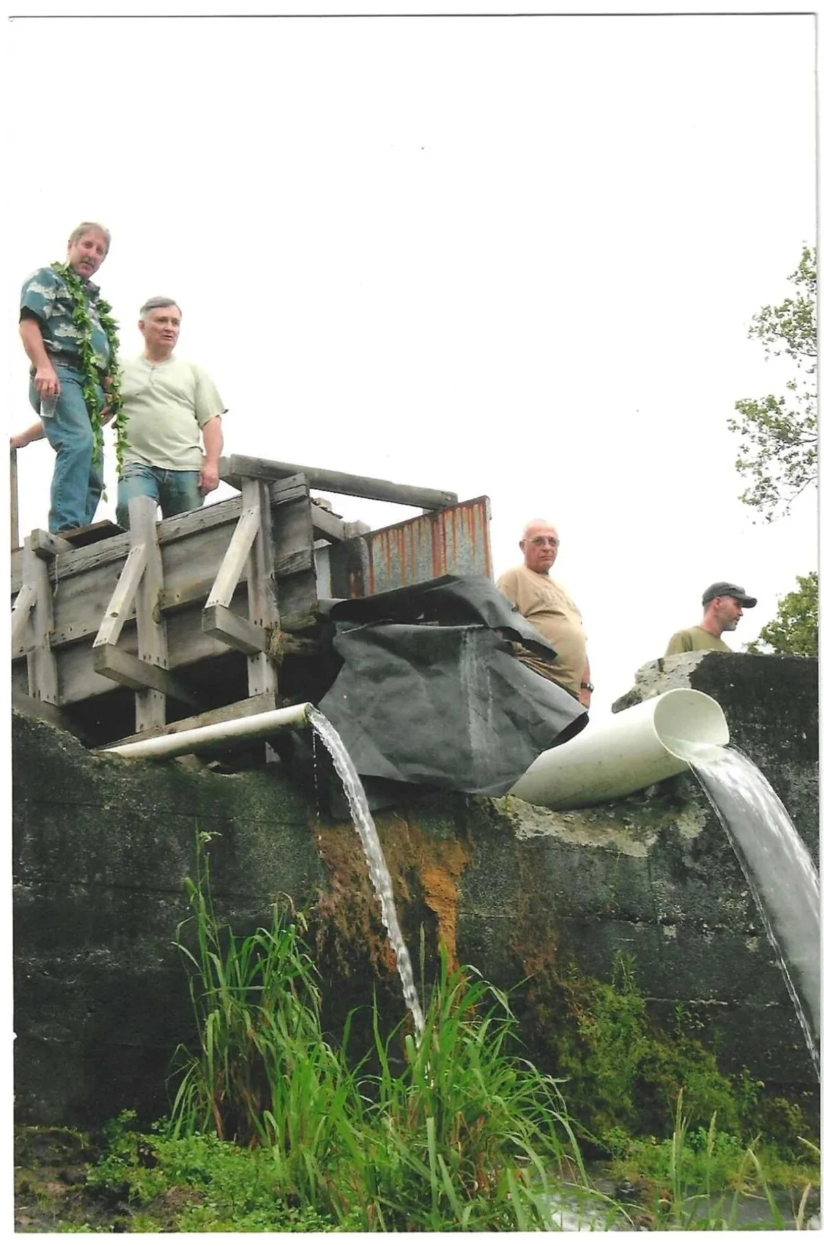 Team members stand above flowing water at part of the Keaīwa water system.