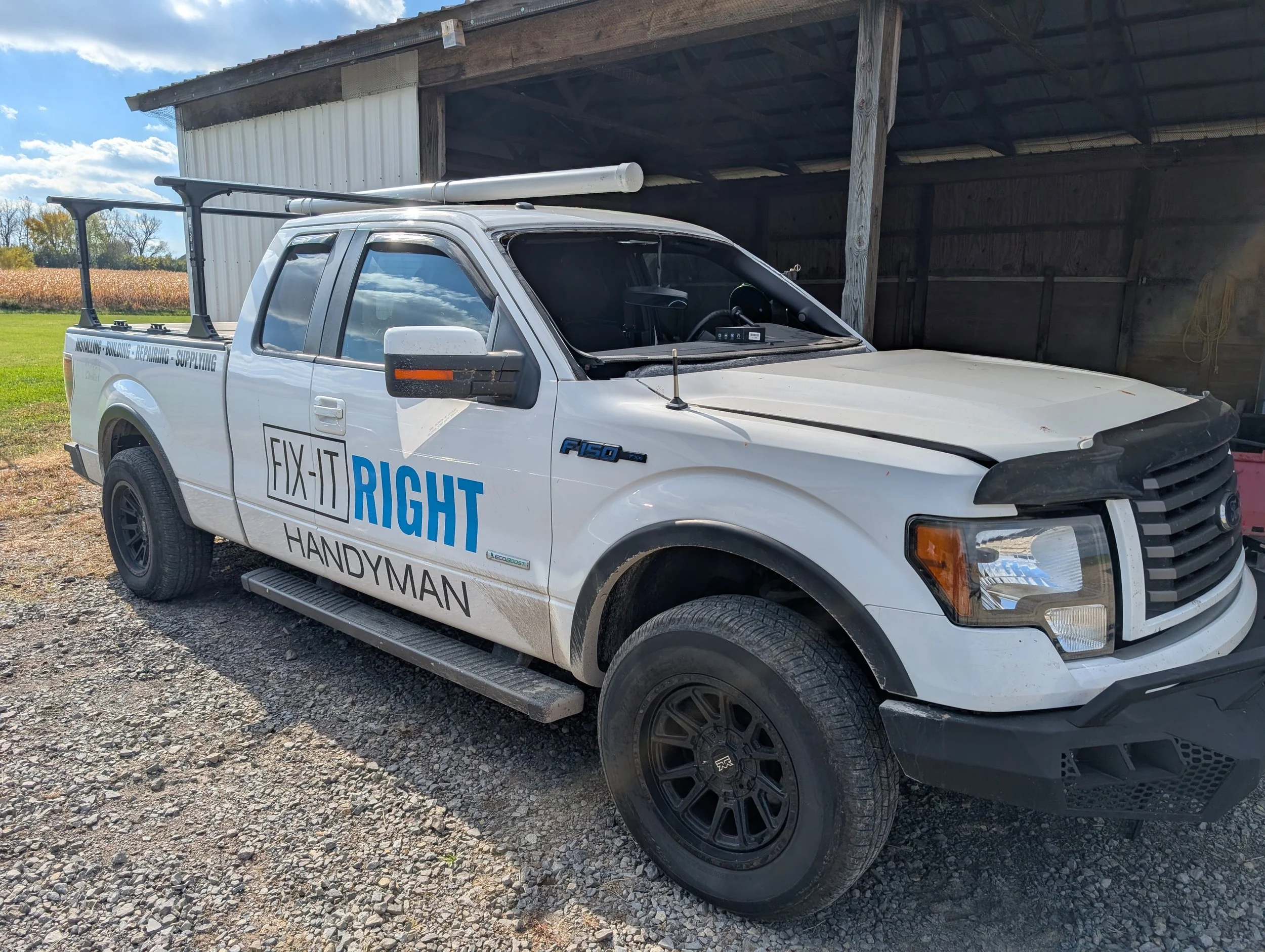 Row of white delivery vans parked in a lot with green trees and blue sky in the background.
