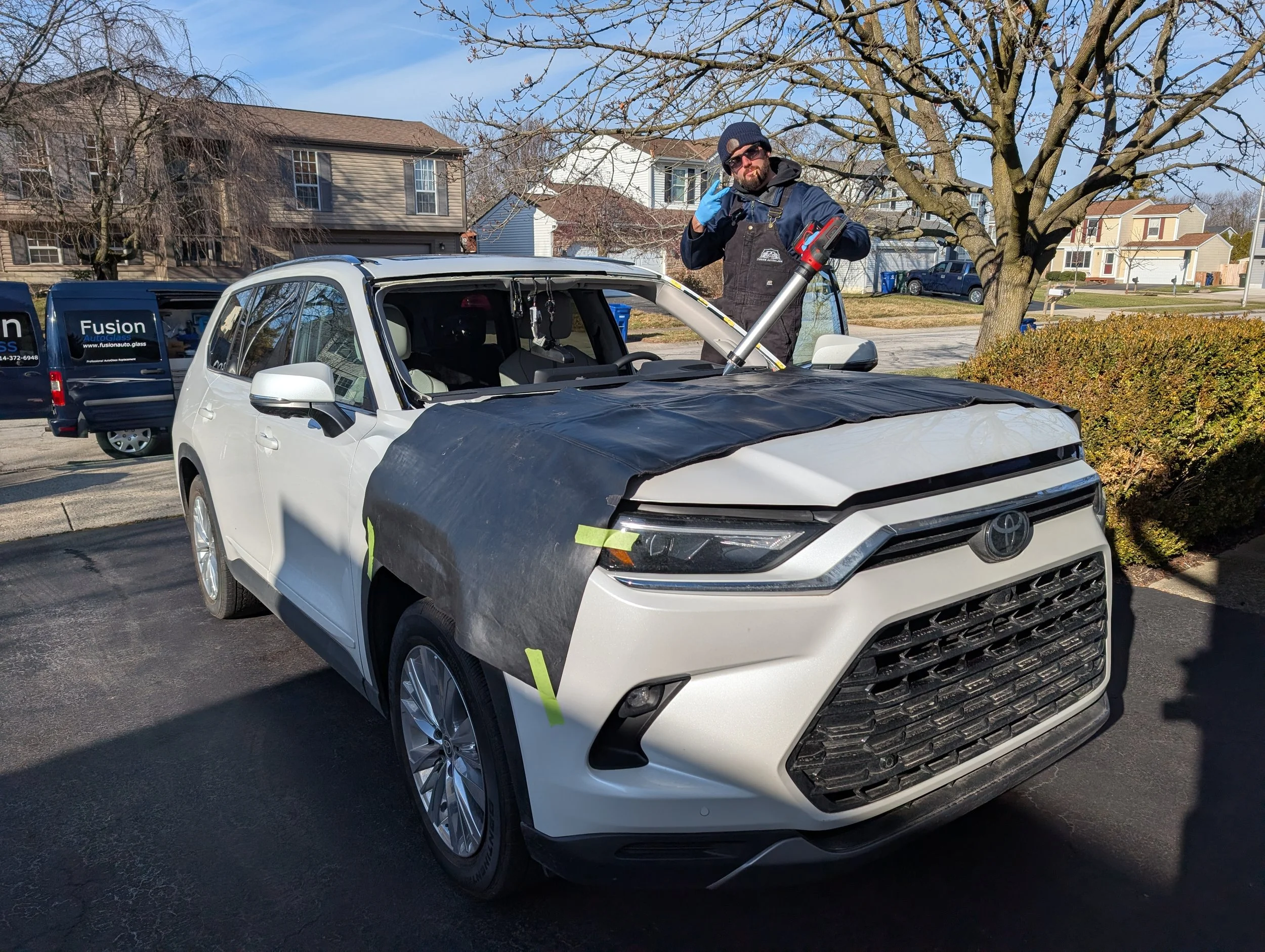 26 Toyota Grand Highlander with its' windshield removed and Trent giving a thumbs up while shooting urethane. 