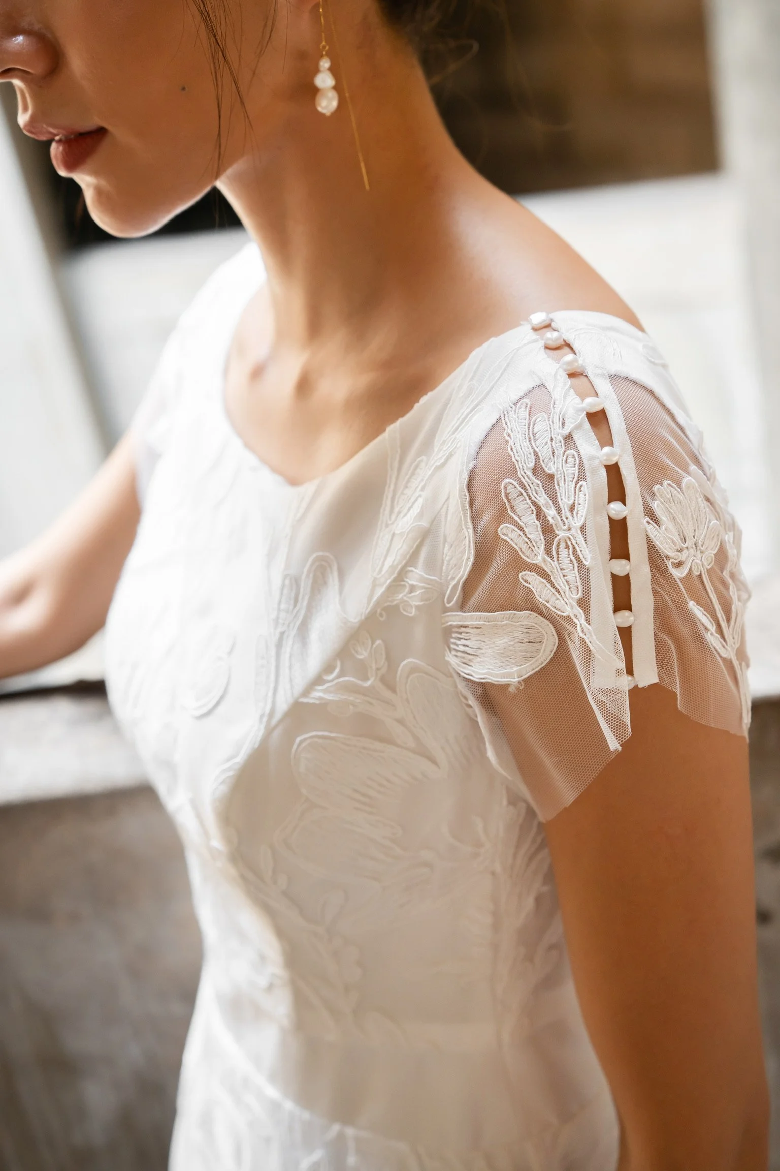Nærbillede af det transparente blondeærme med blomstermotiver på Simone-brudekjolen
