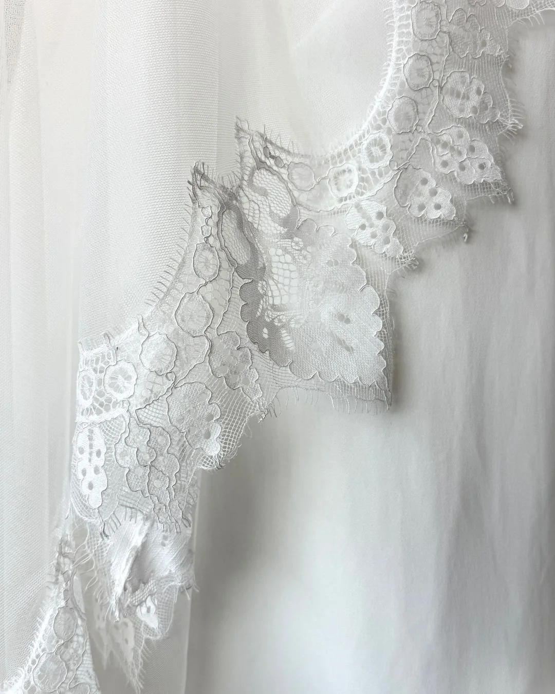 Eksklusivt brudeslør med håndsyede blonder, der tilfører et romantisk og sofistikeret udtryk. De fine detaljer langs kanten skaber en smuk, feminin afslutning til dit brudelook