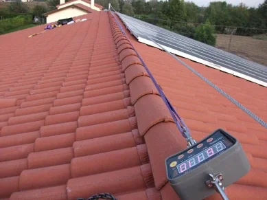 Tetto con tegole rosse e pannelli solari, con dispositivo di misurazione montato su una delle tegole.