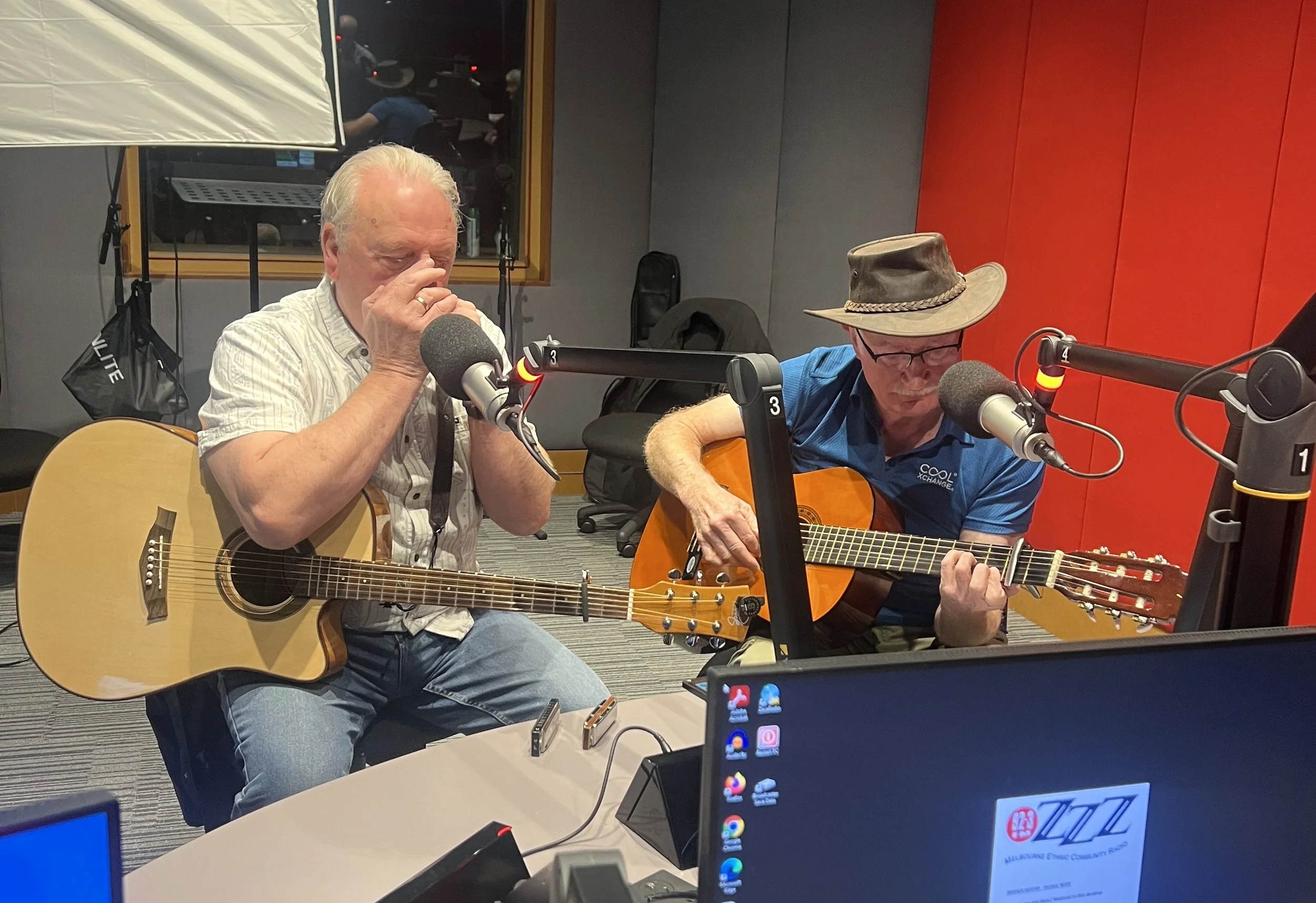 two men playing guitars in a radio studio