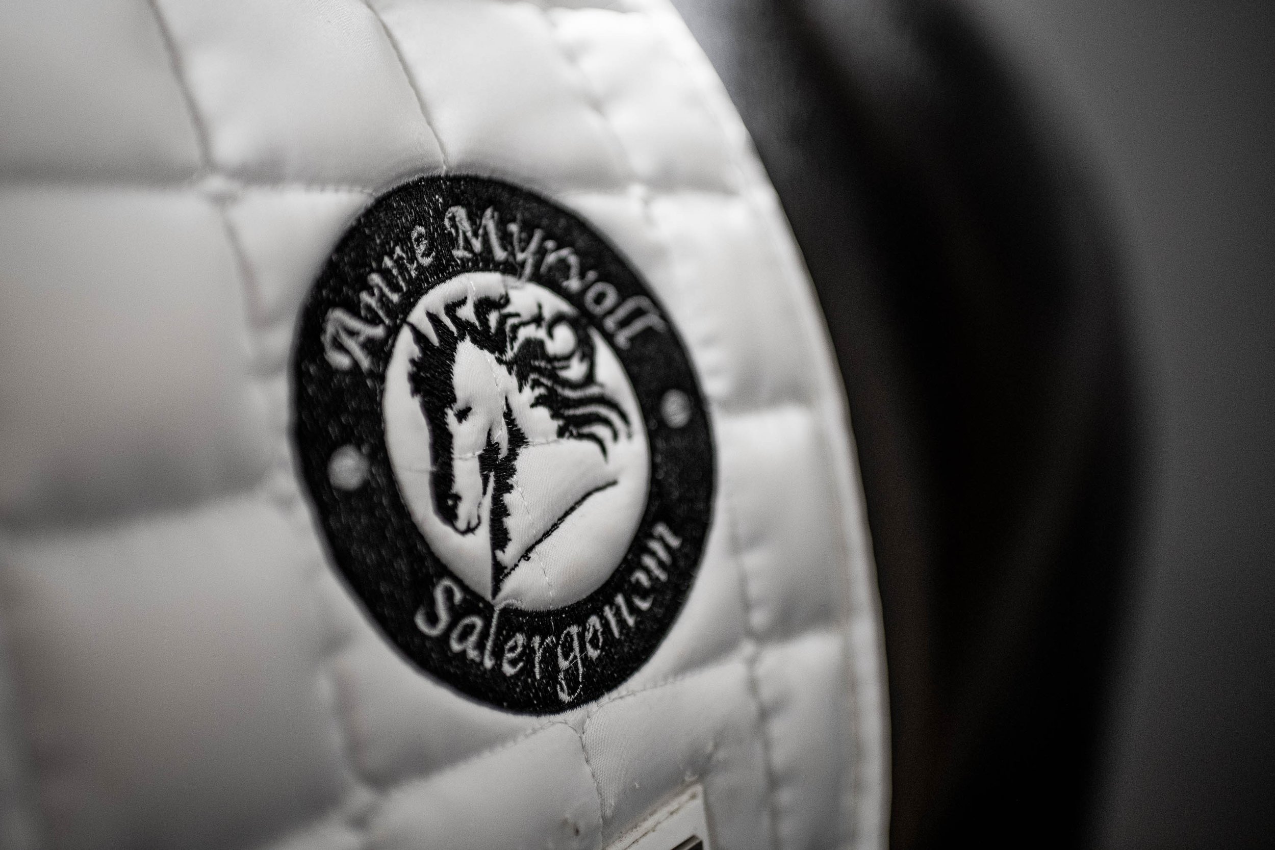 Et svart-hvitt bilde av et metallskilt med en logo av en hest.