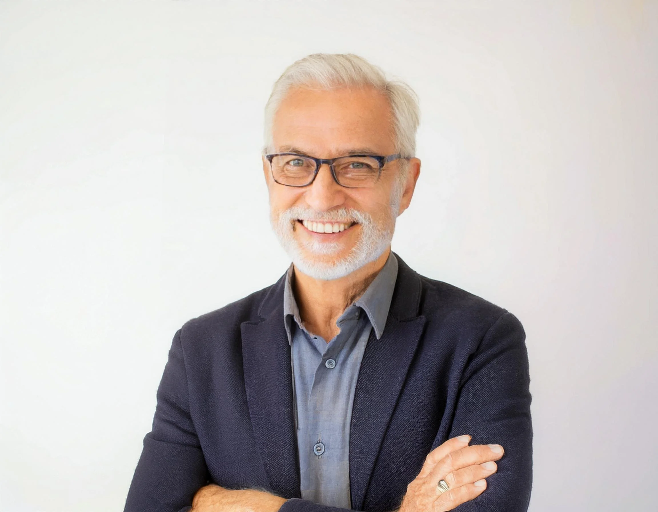 Smiling professional man with glasses and beard wearing a blazer.