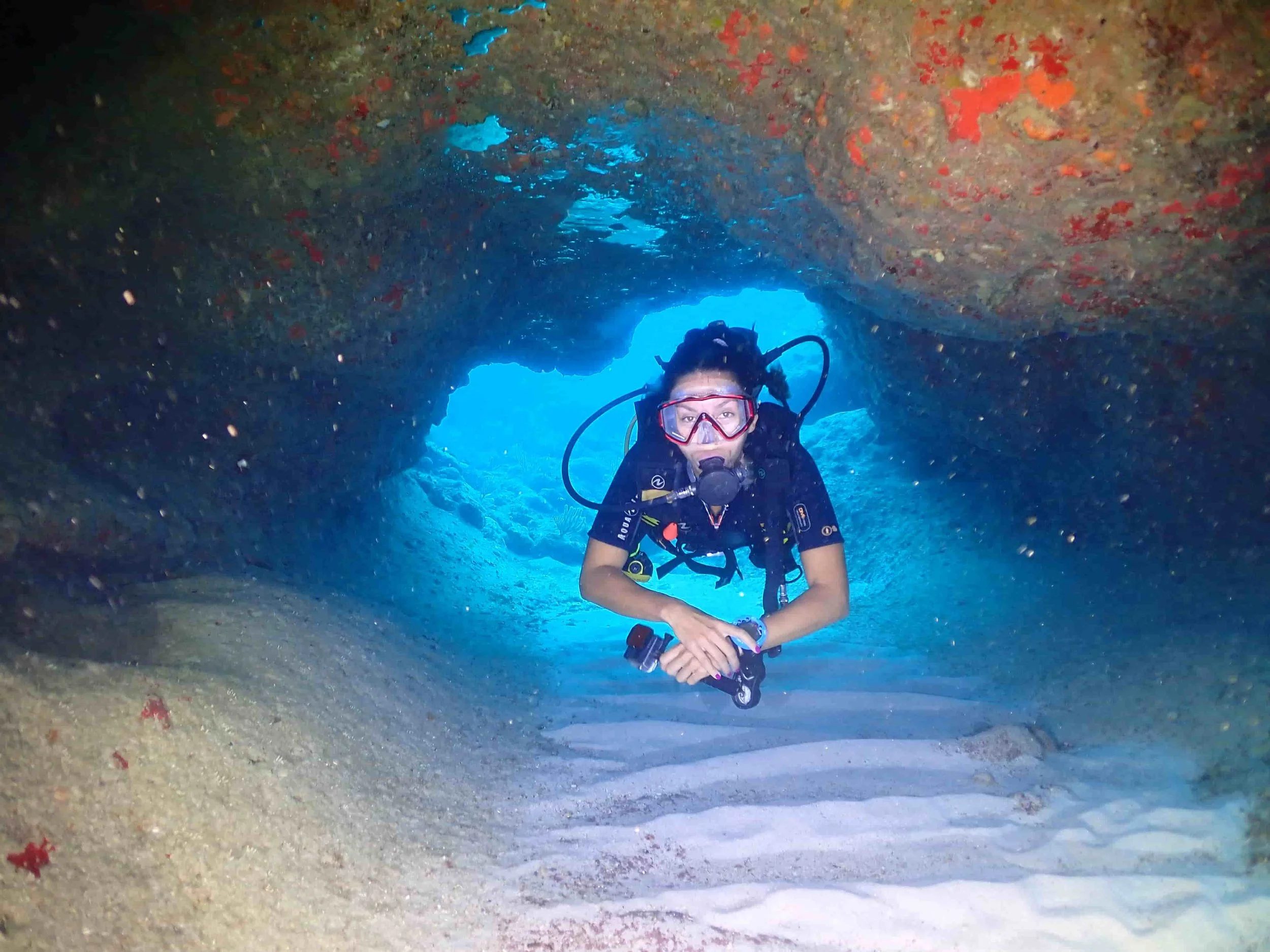 diver passing trough a reef cave in tulum mexico