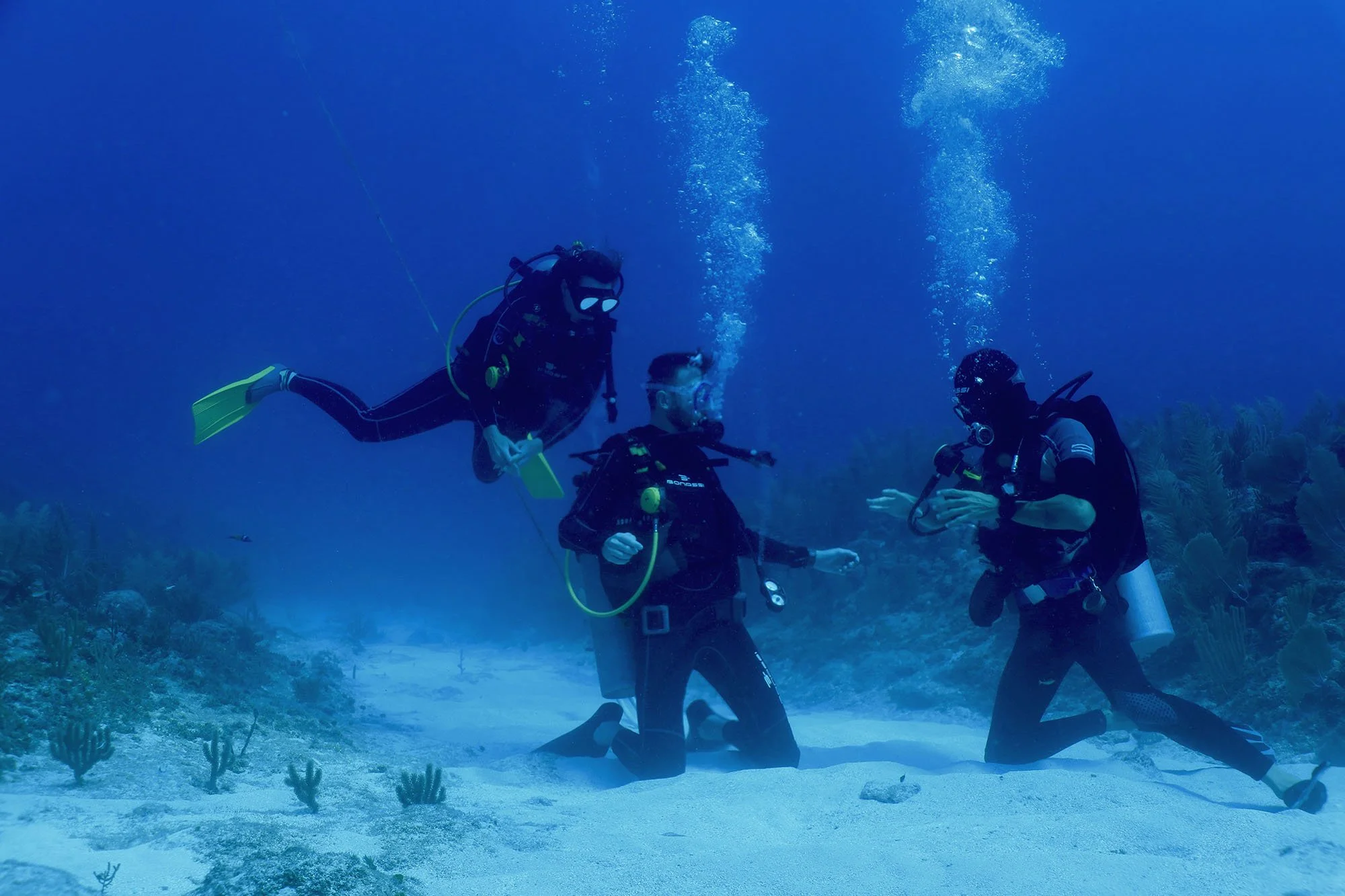 Three scuba divers underwater, making excercises underwater