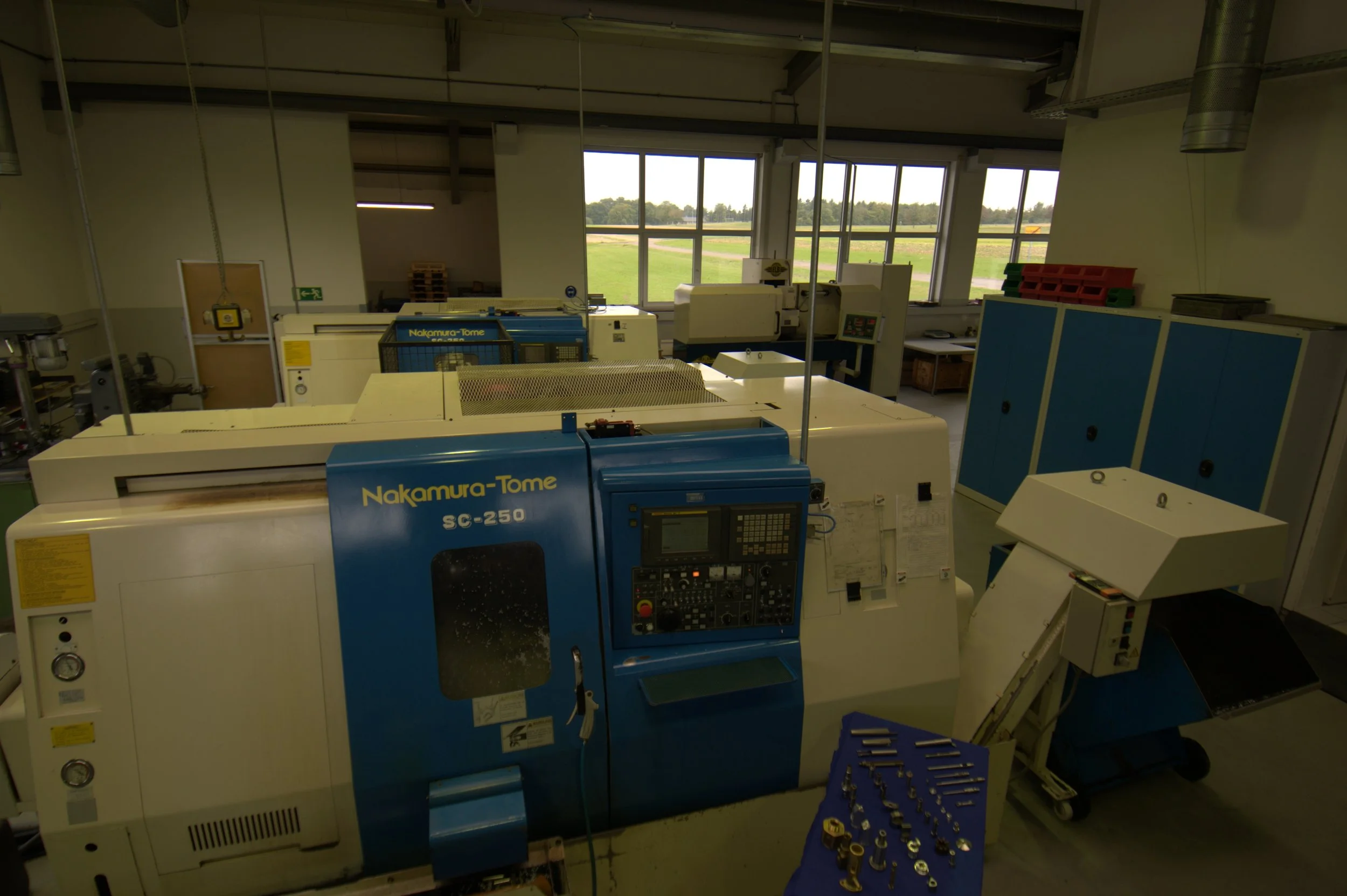 Industrielle CNC-Maschine in einer Werkstatt, mit Werkzeugen auf einem Tisch davor.