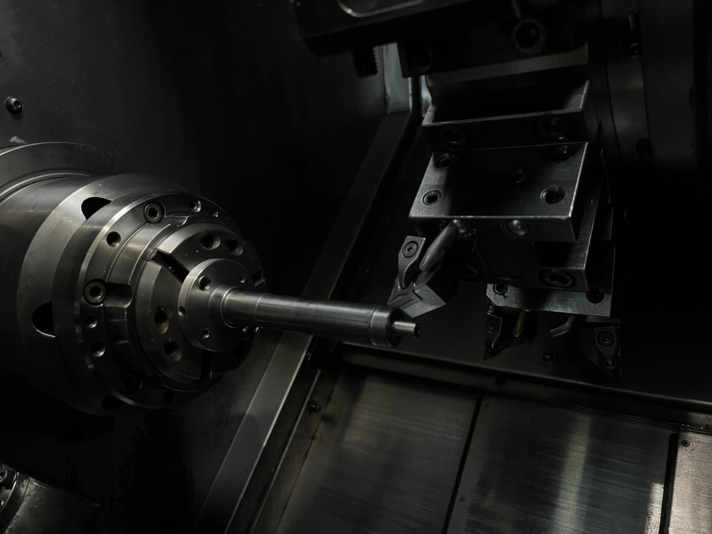 Nahaufnahme eines CNC-Maschinenhauptteils mit laufendem Schneidkopf, der eine Metallstange hält.