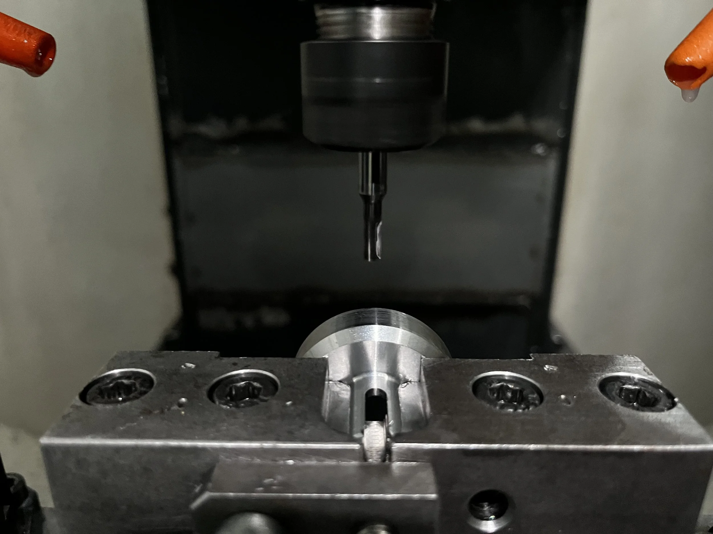 Ein metallisches Werkzeug, das sich an einer Maschine befindet, die für präzises Bohren oder Fräsen verwendet wird, mit einem metallischen Werkstück in der Mitte.