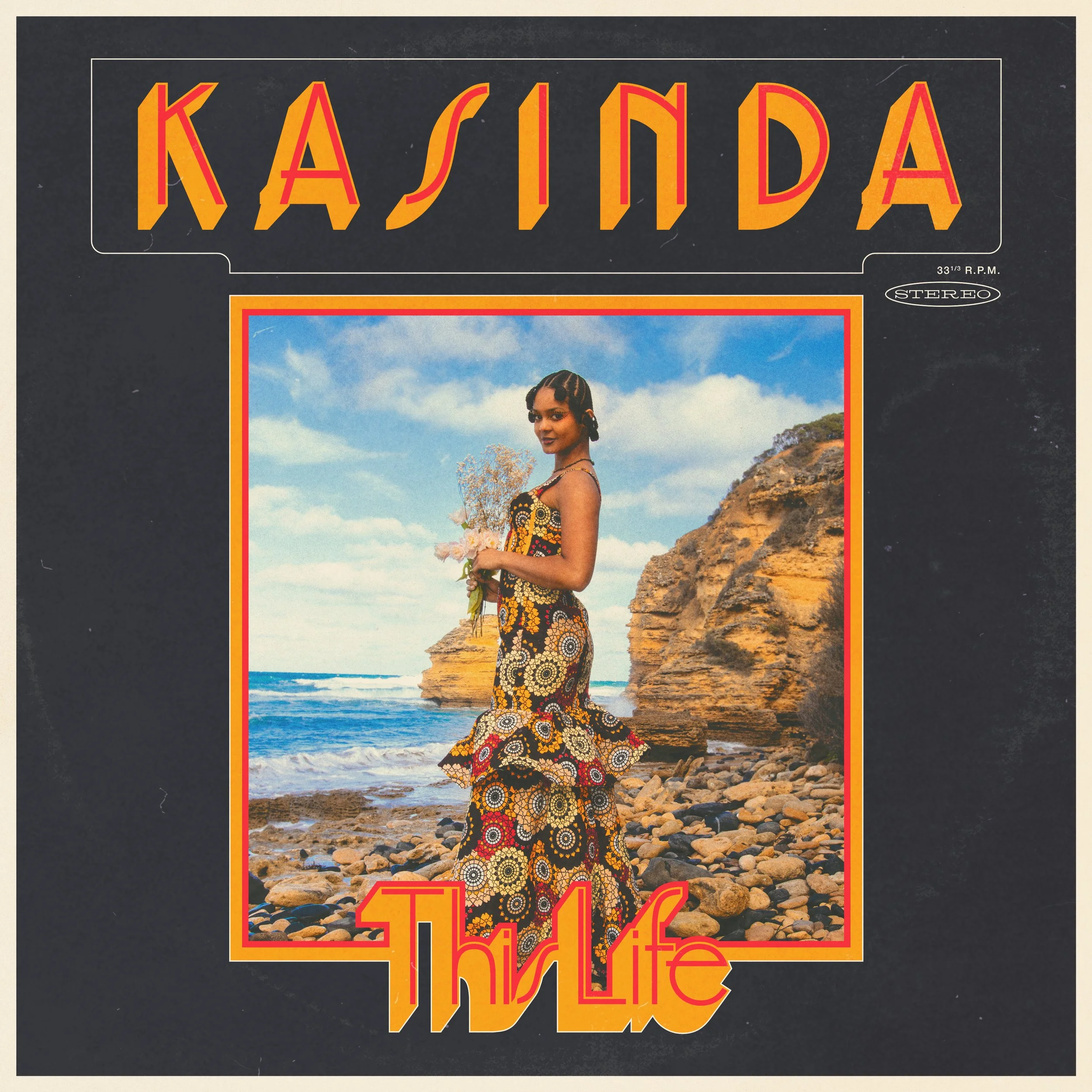 Vintage promotional poster for a musical performance or album featuring a woman in a colorful, patterned dress standing on rocky beach, with cliffs in the background and a partly cloudy sky.