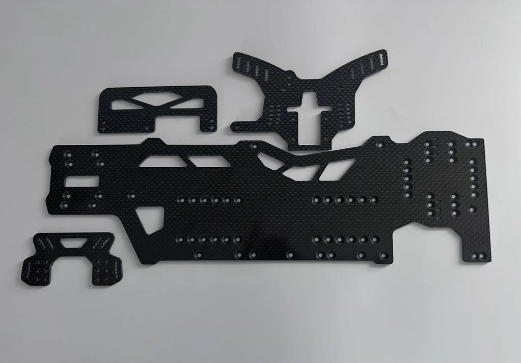 Set of black carbon fiber parts for a remote-controlled car on a white background.