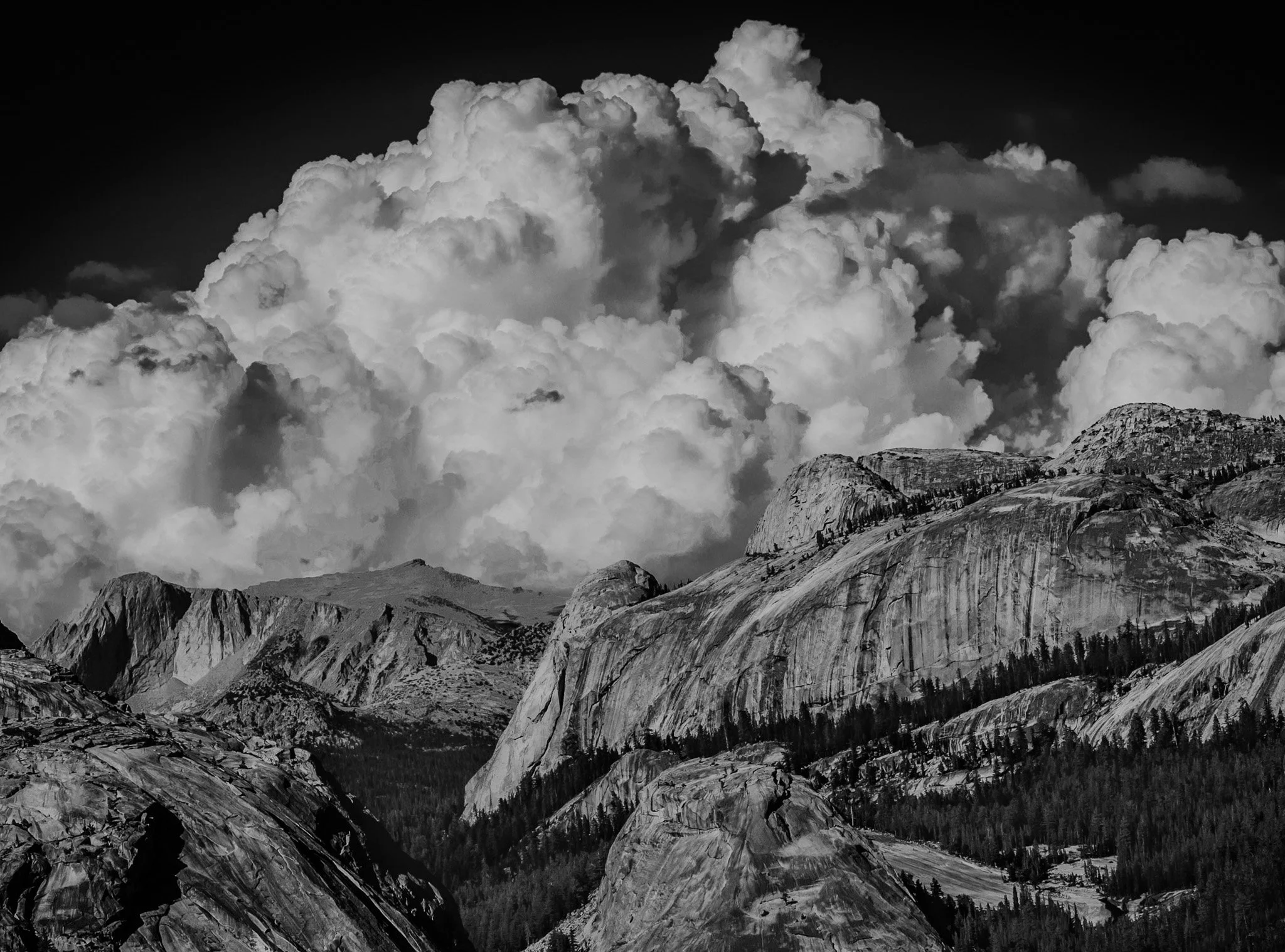 Black and white photo of massive, dramatic thunderhead clouds towering over granite peaks in Yosemite's high country.