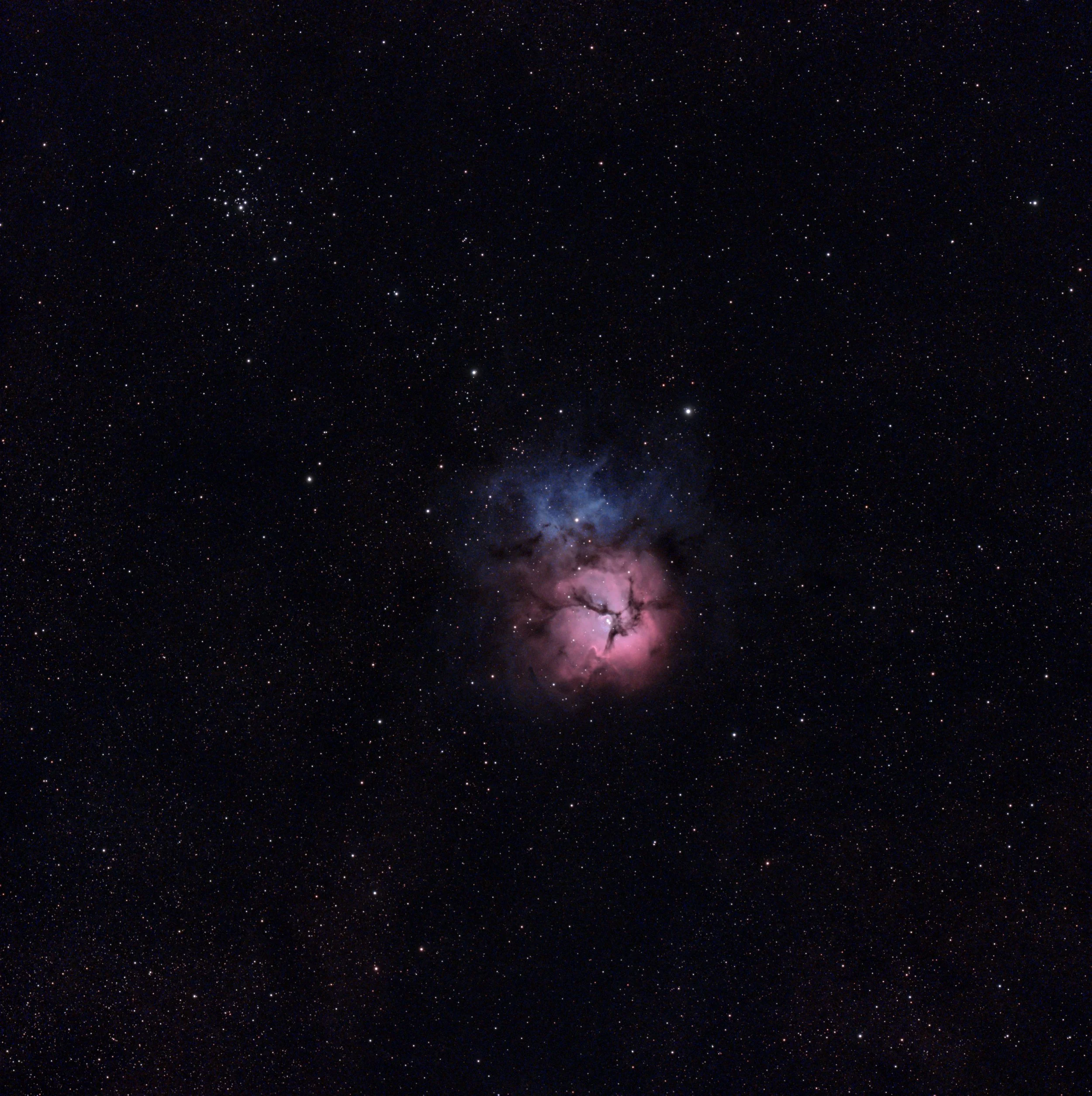 A deep-space view of the Trifid Nebula featuring a glowing pink emission core, blue reflection nebula, and dark dust lanes against a starfield.
